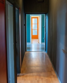 A hallway with wooden floor and orange door