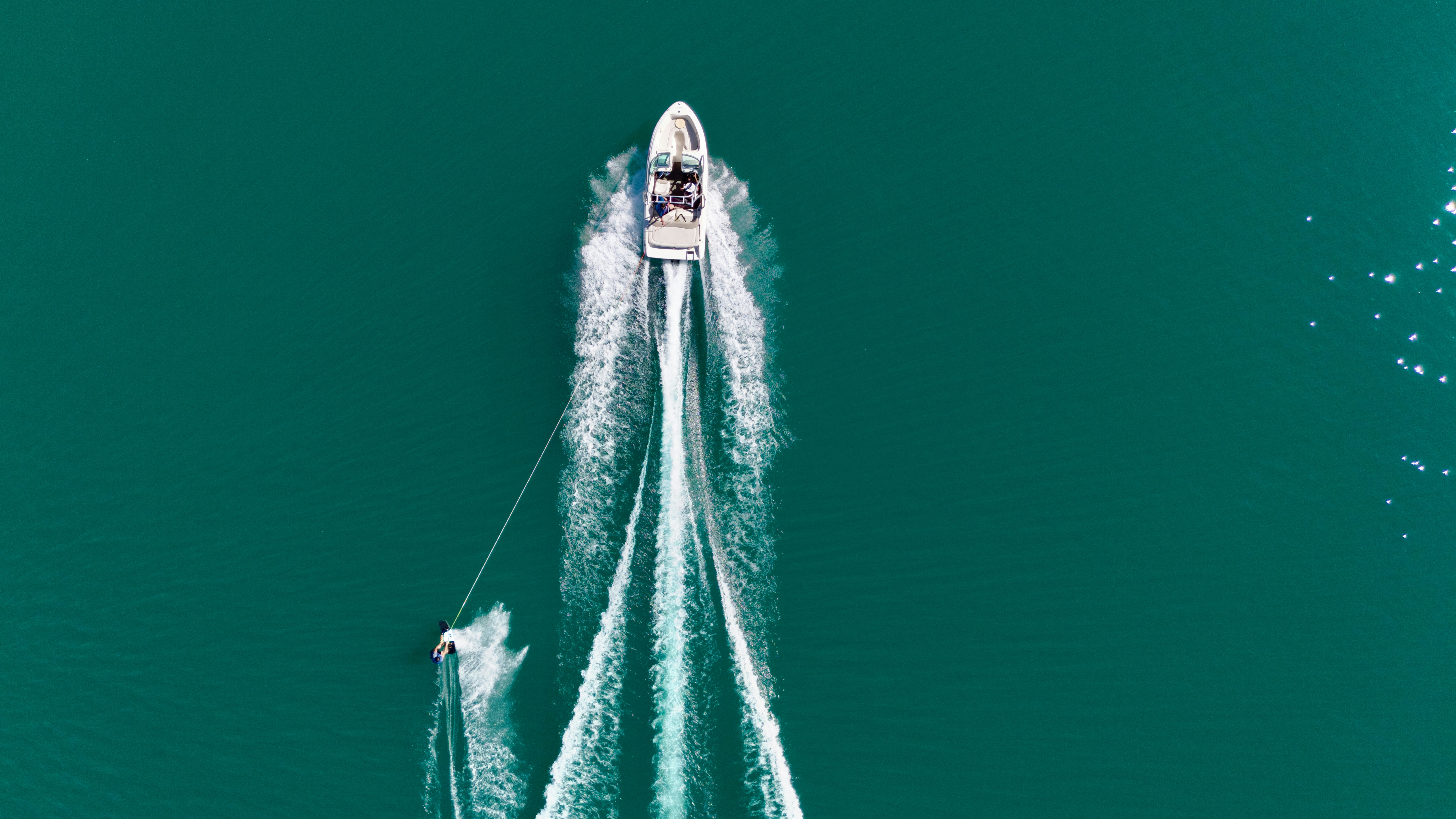 Boat pulling a water skier across turquoise water