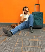 Man sitting on floor with suitcase, looking distressed.