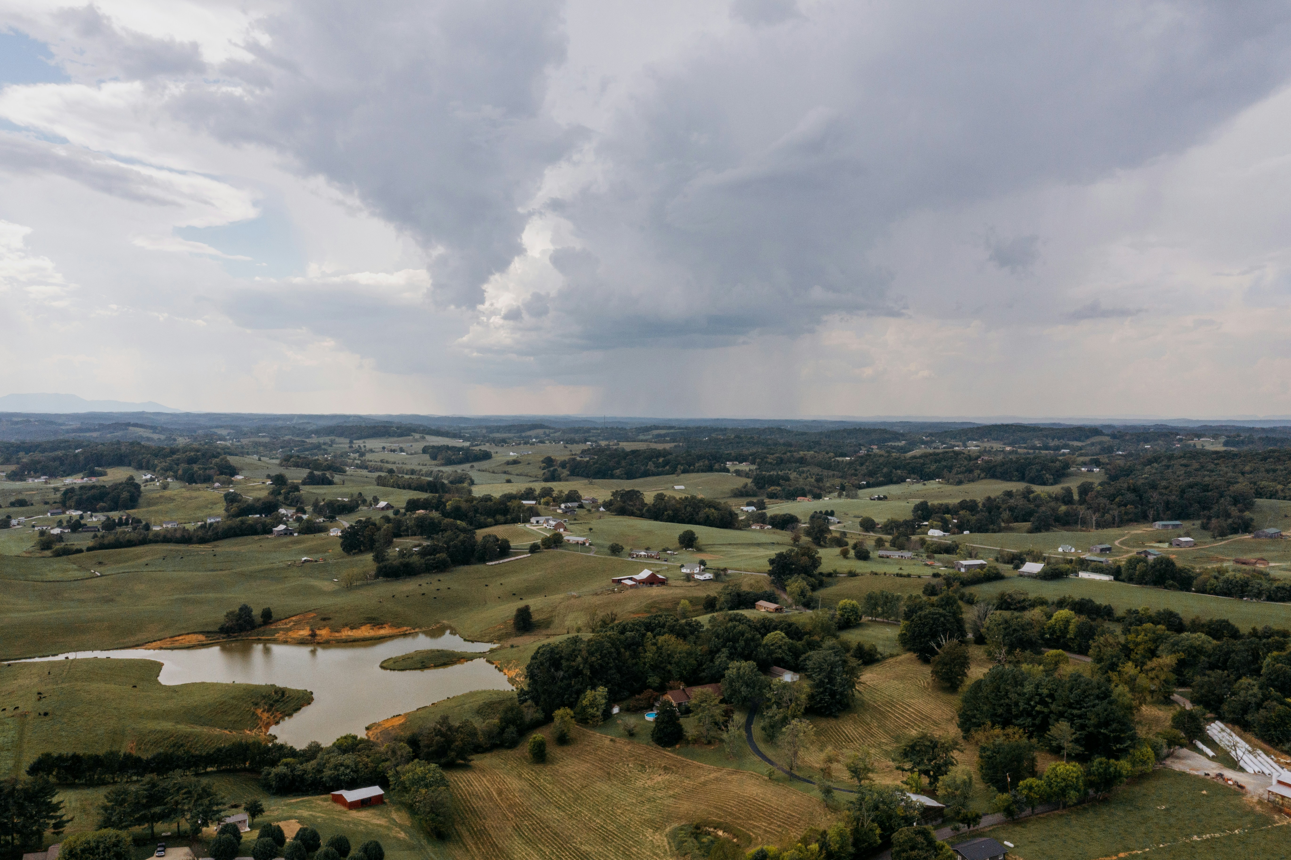 Rolling hills and farmland under stormy sky