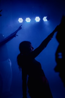 Silhouettes of people dancing under blue lights.