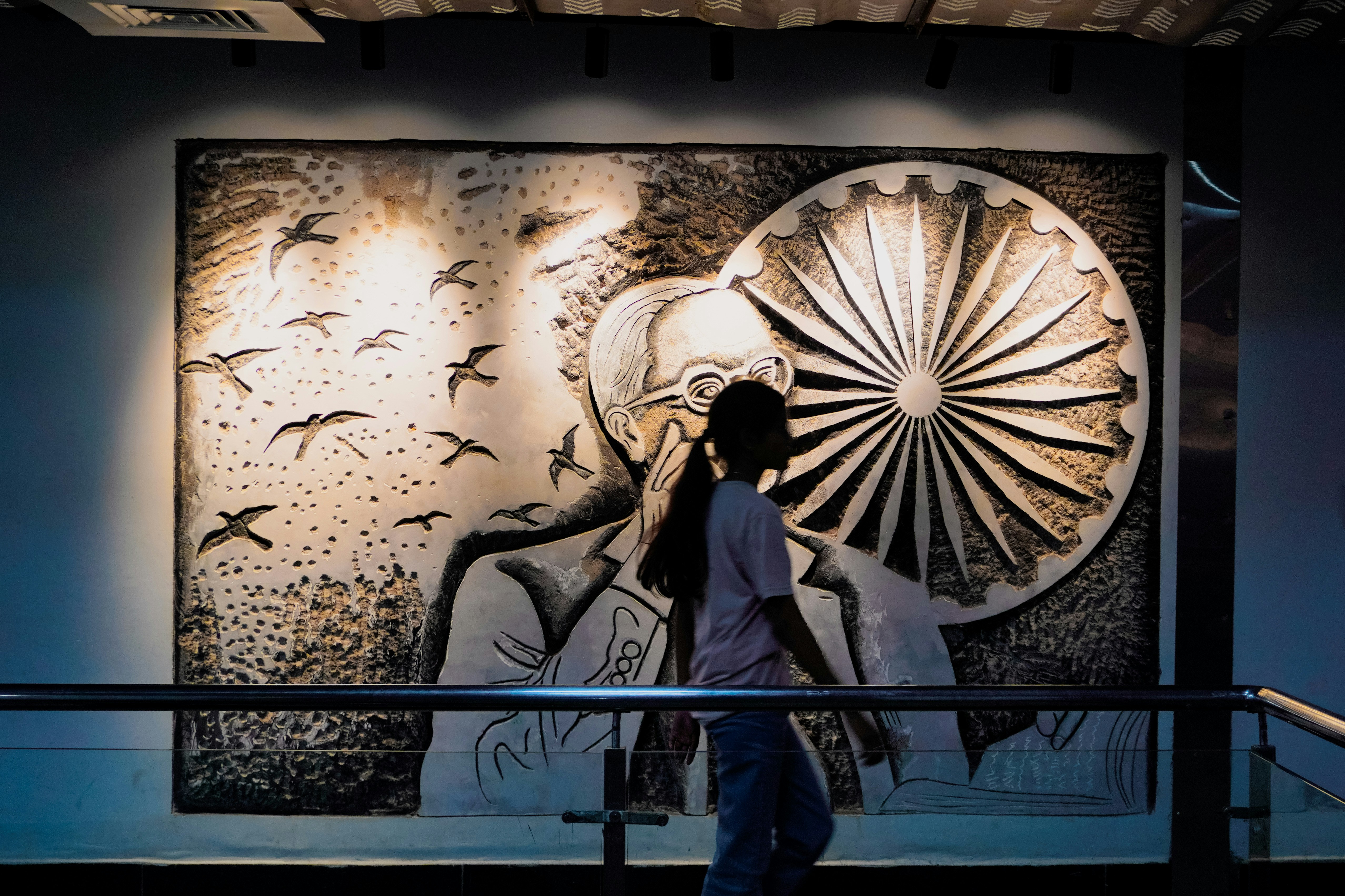 Person walks past large mural of mahatma gandhi