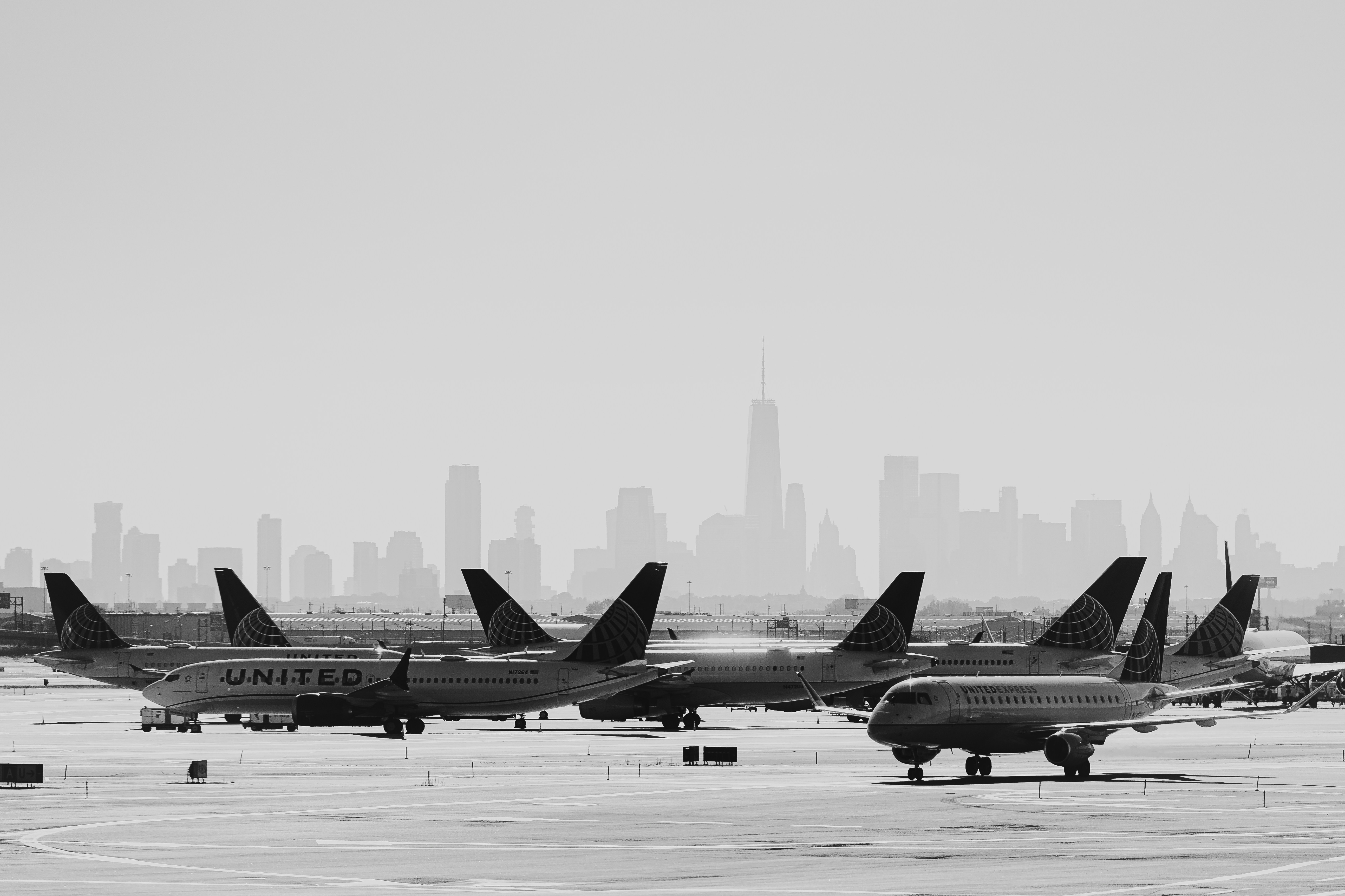 Airplanes parked at an airport with cityscape background.