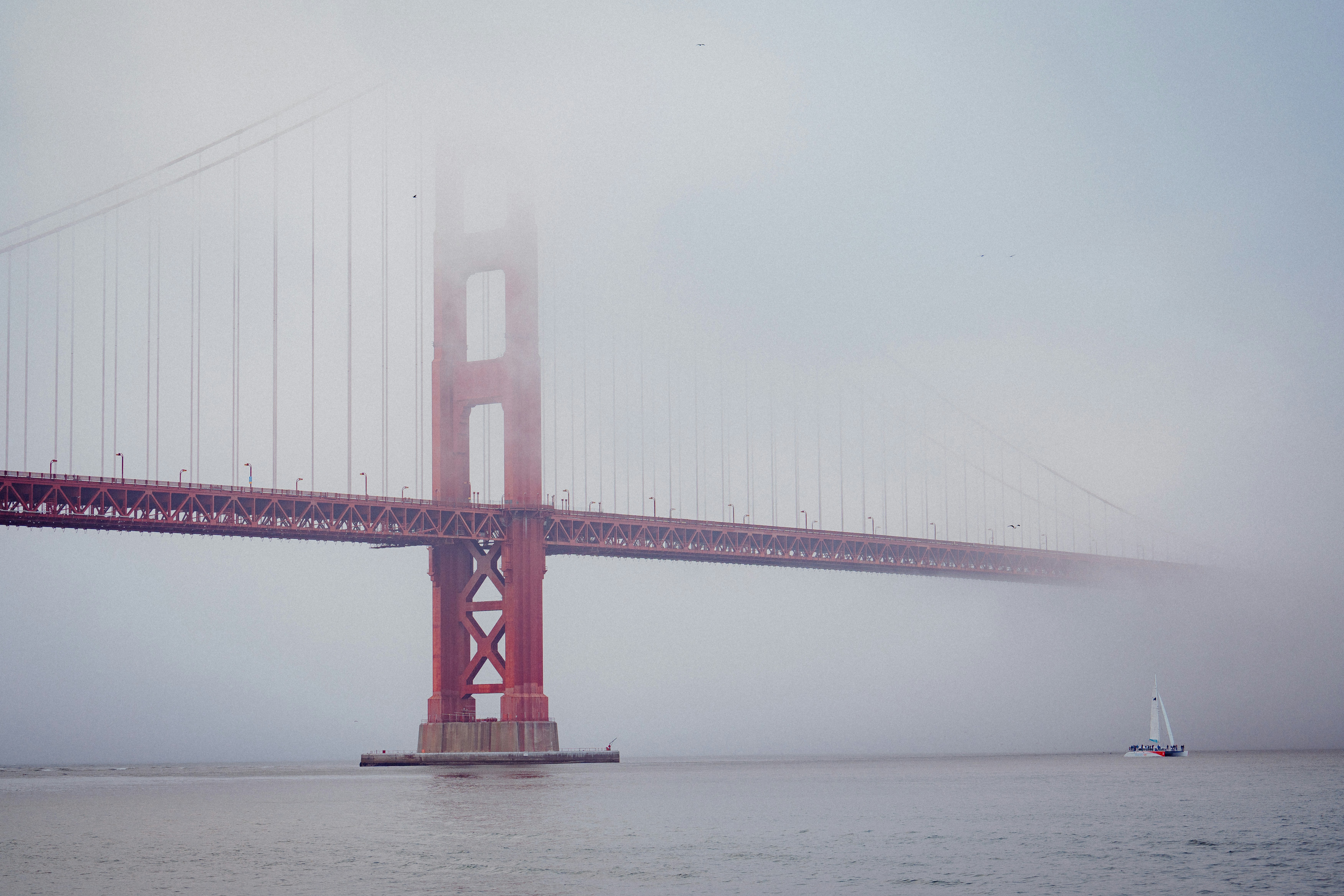 Golden gate bridge shrouded in fog with sailboat