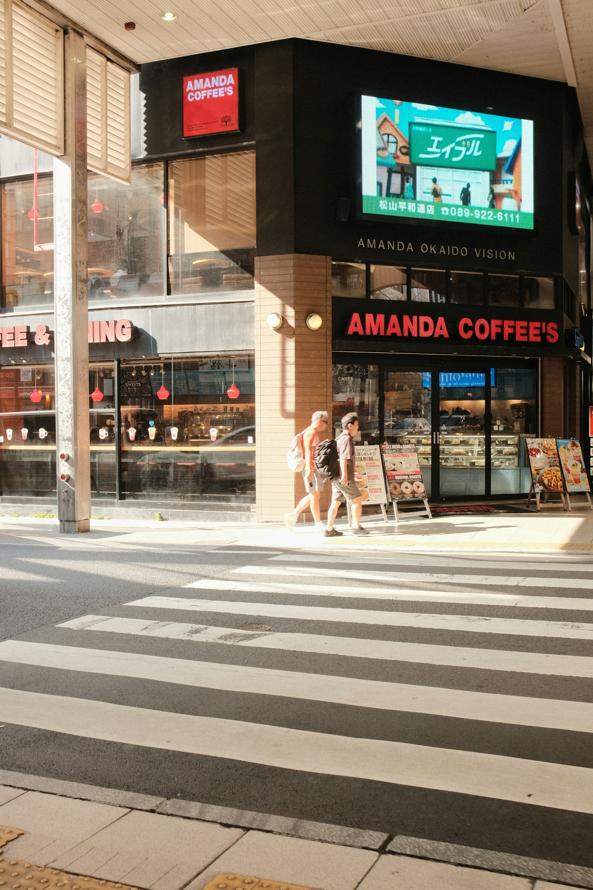 Two people walk past amanda coffee's storefront.