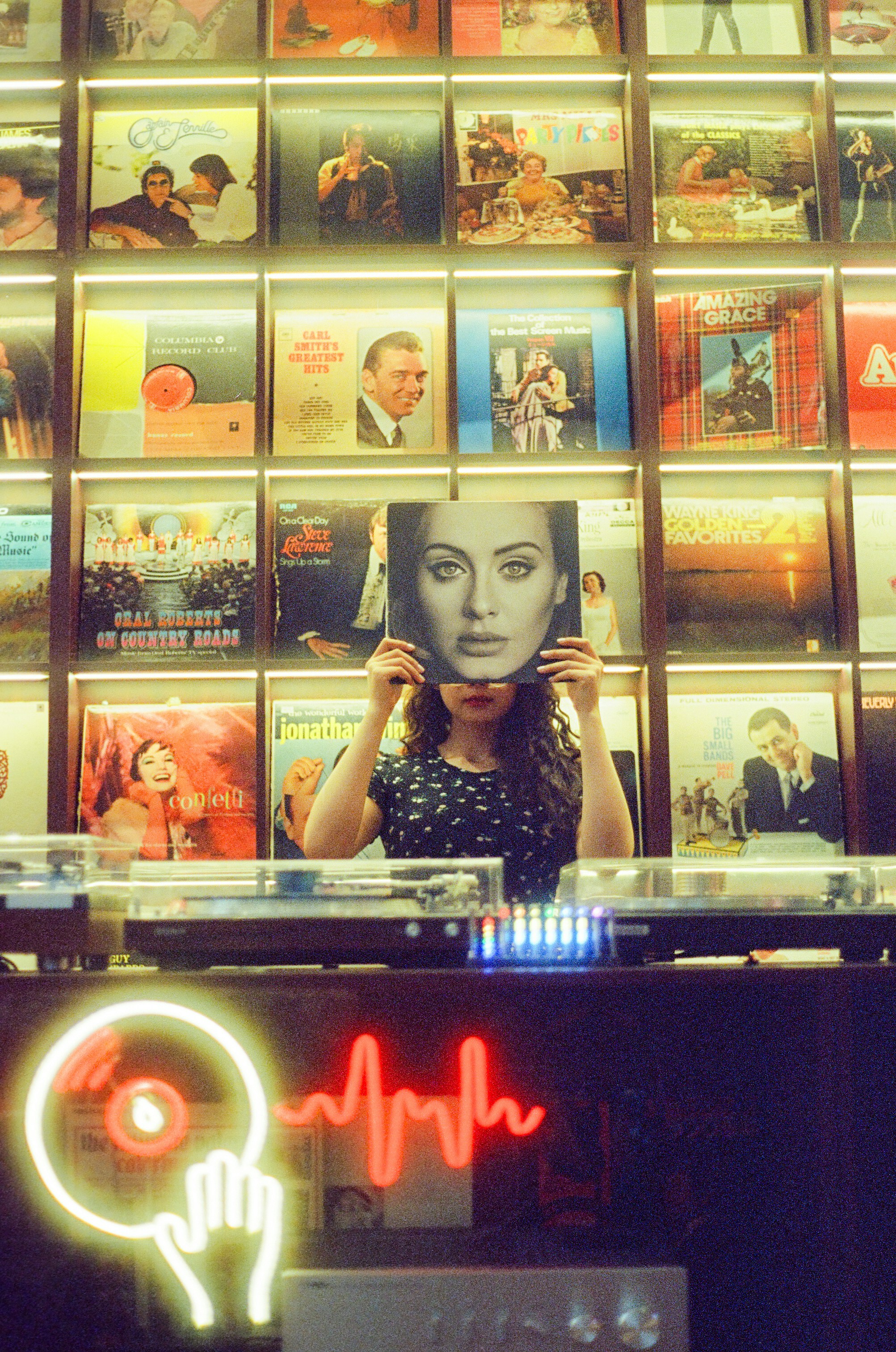 Woman holding adele album in front of vinyl records