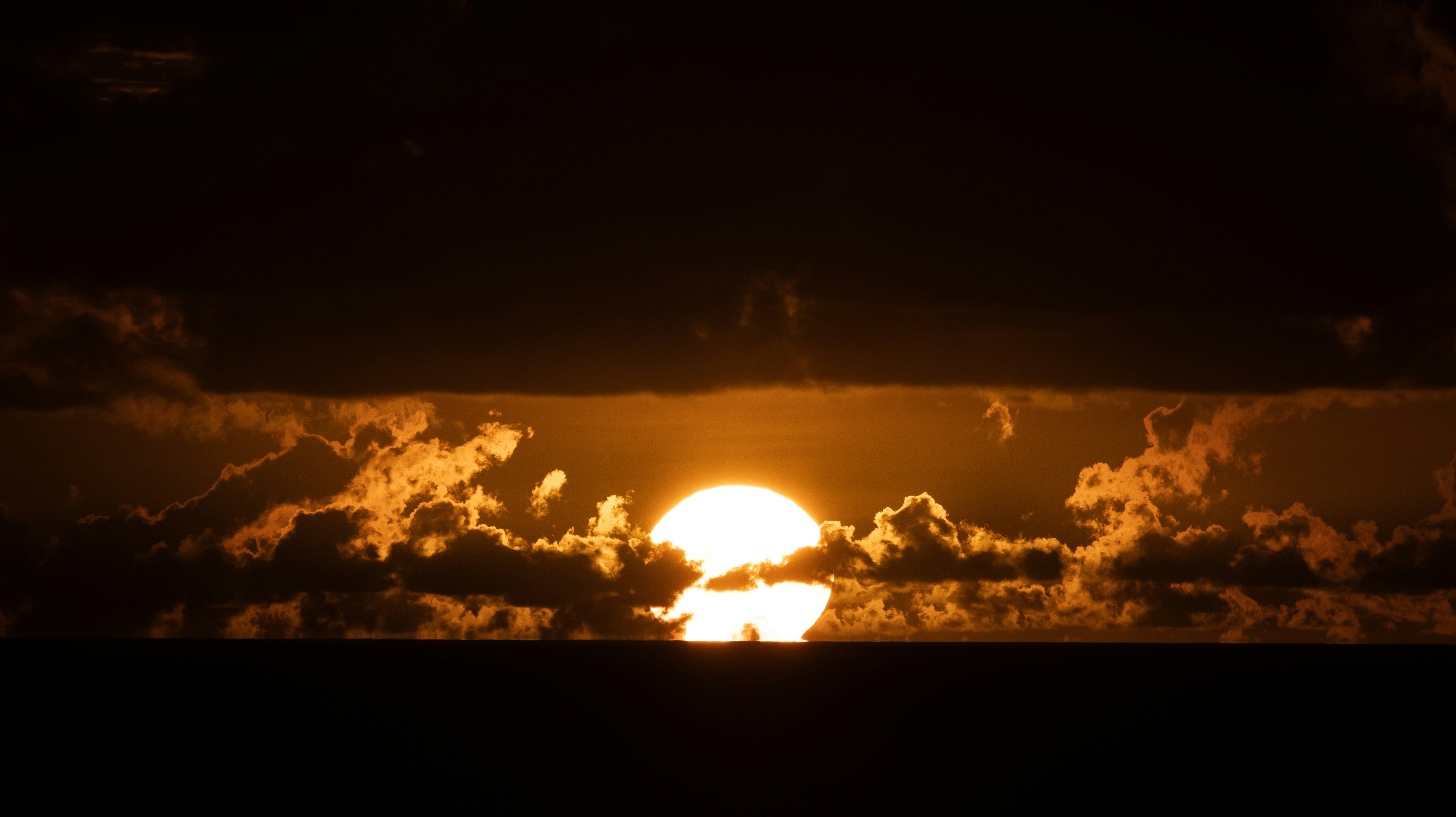 Sun setting over the ocean with dramatic clouds