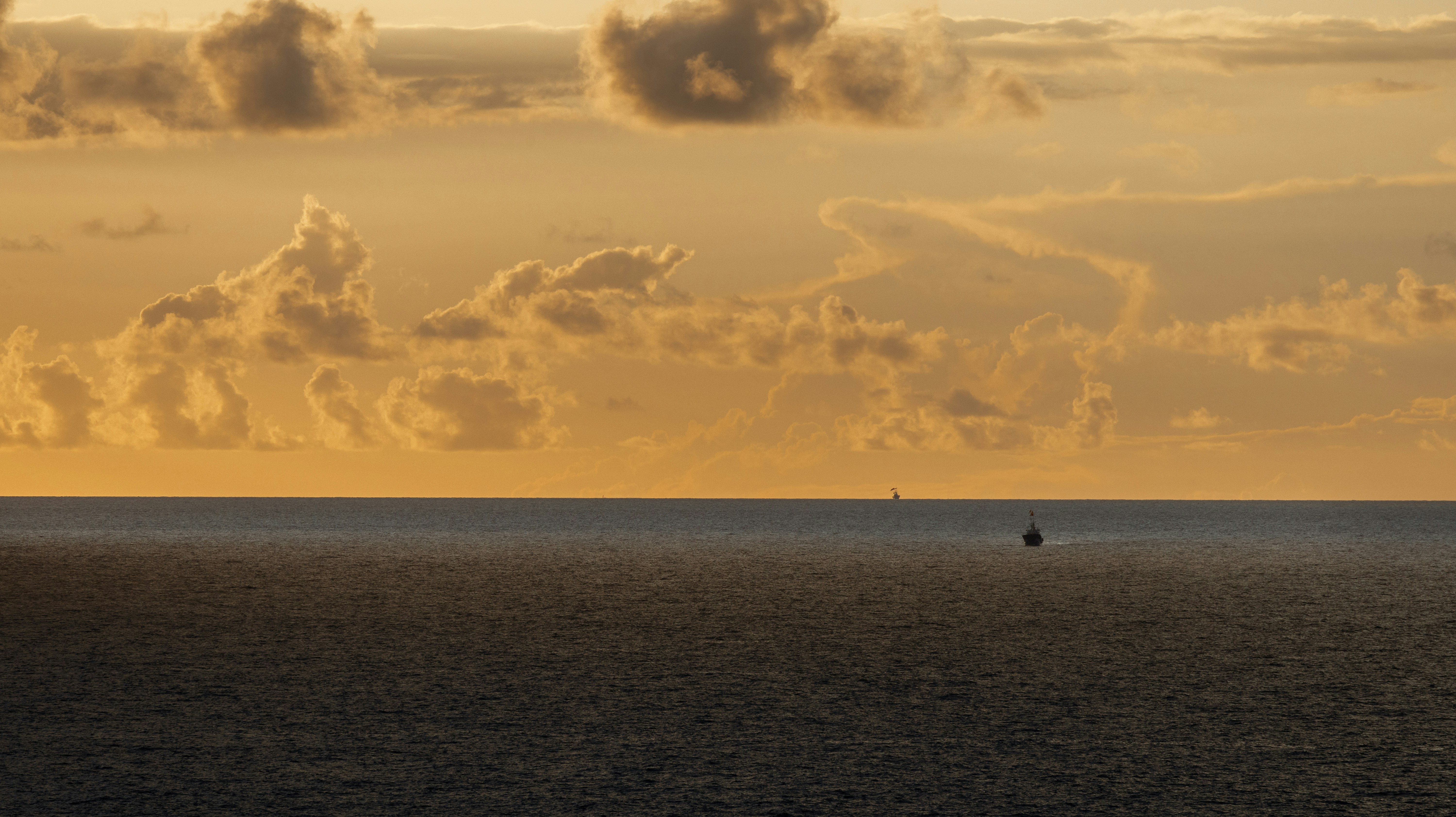 Golden sunset clouds over a calm ocean horizon