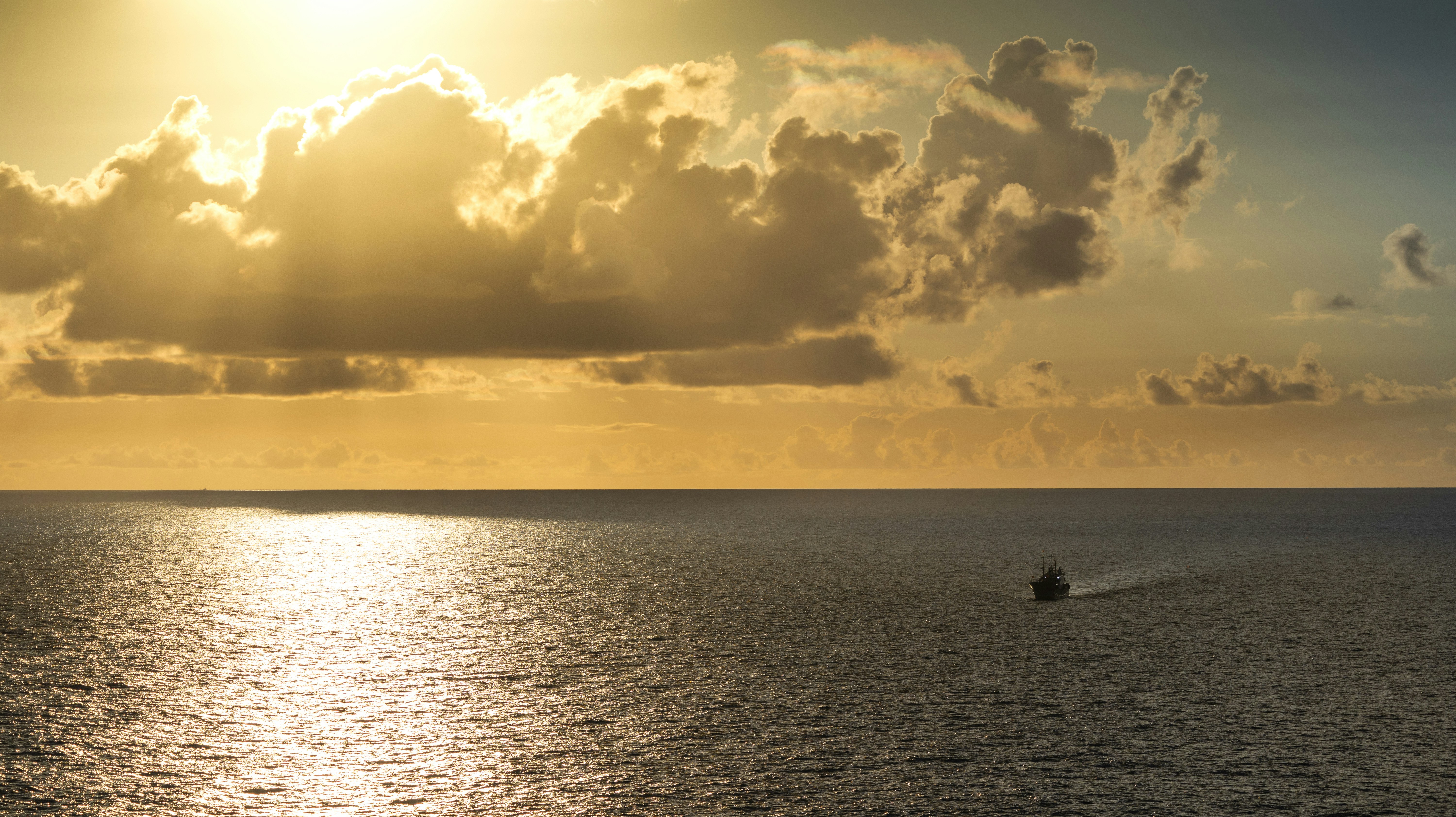 Golden sunset over the ocean with a distant boat.