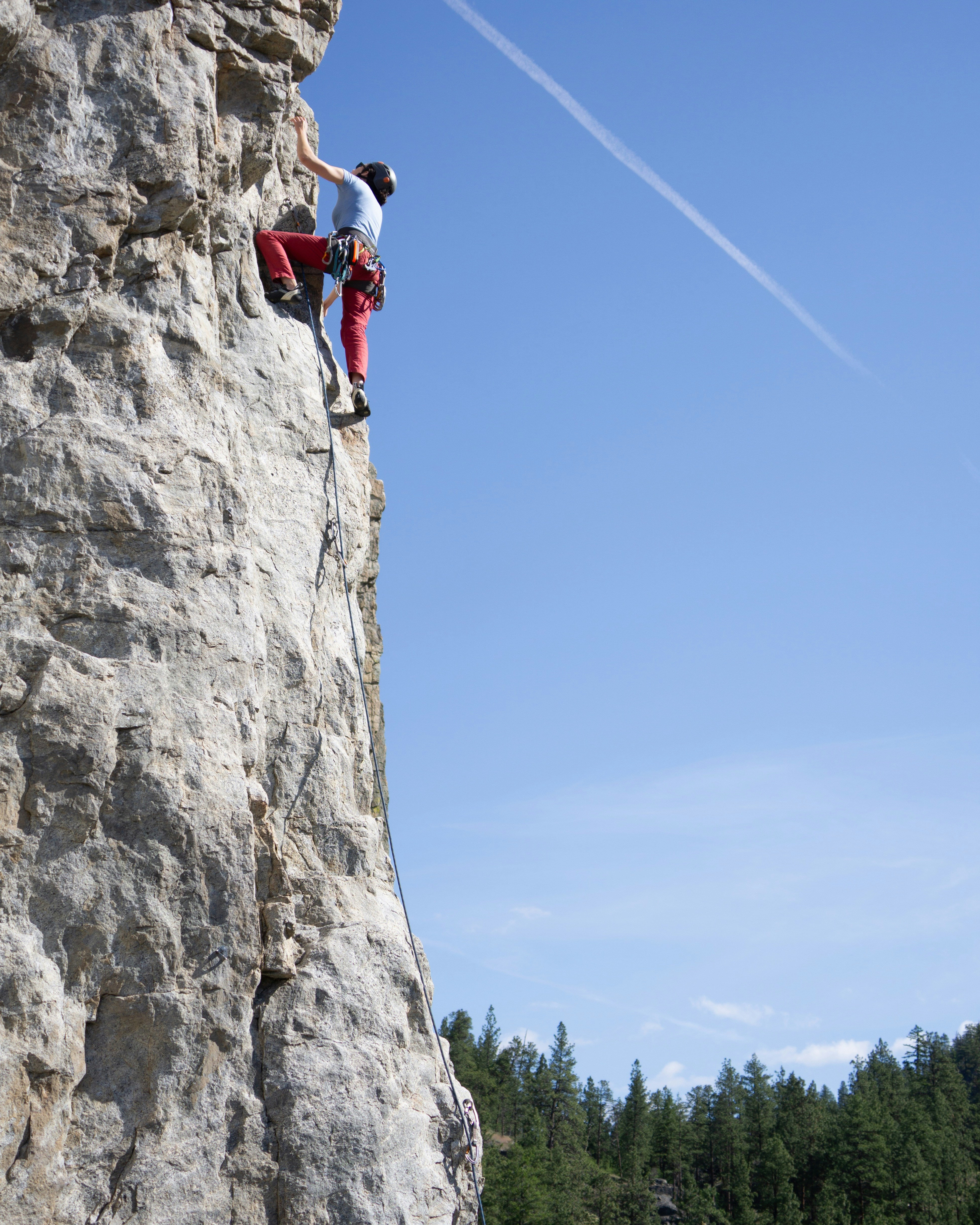 A rock climber scales a steep cliff face outdoors.