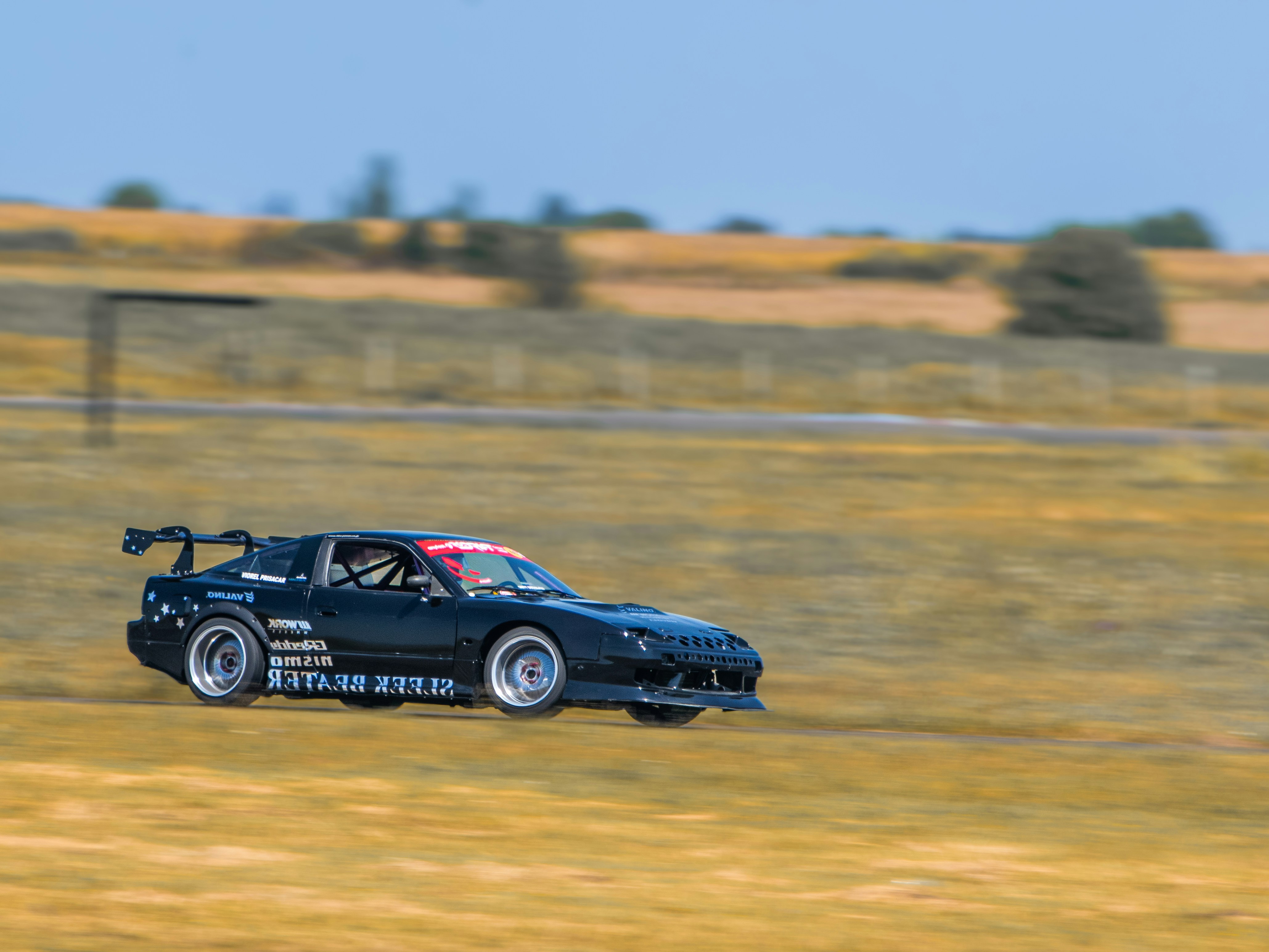 Black sports car racing on a dry track.