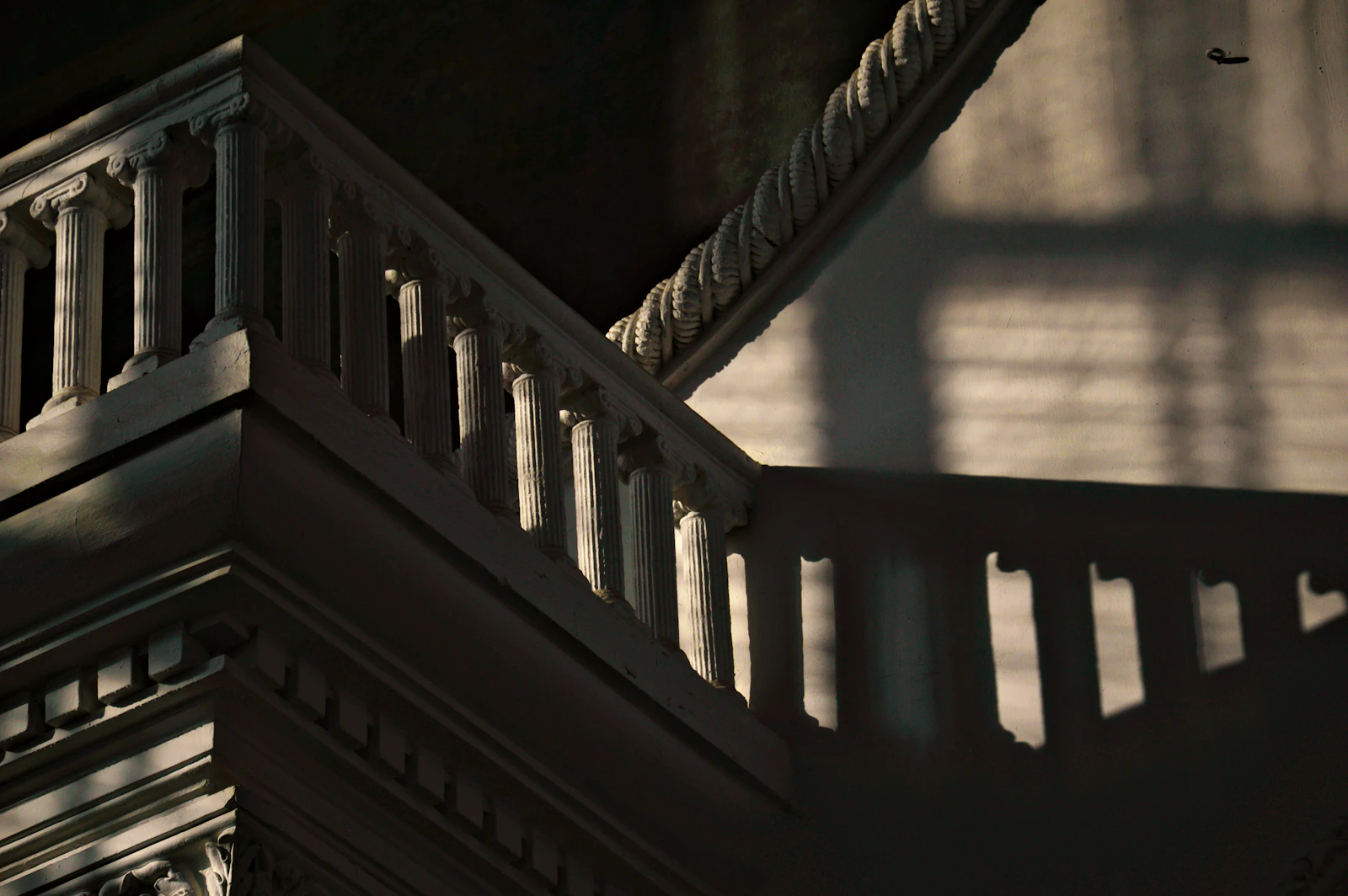 Ornate staircase with shadows cast by window blinds