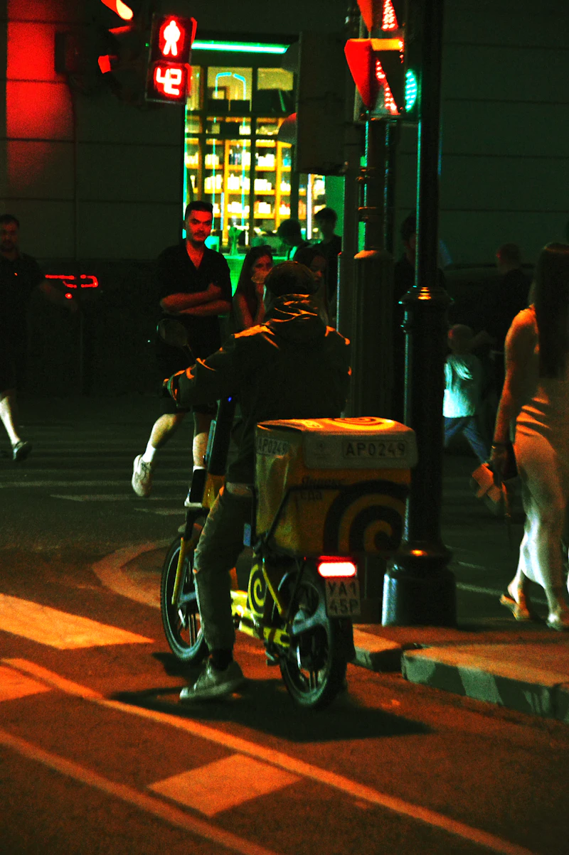 Delivery person on electric scooter at a glowing city intersection at night