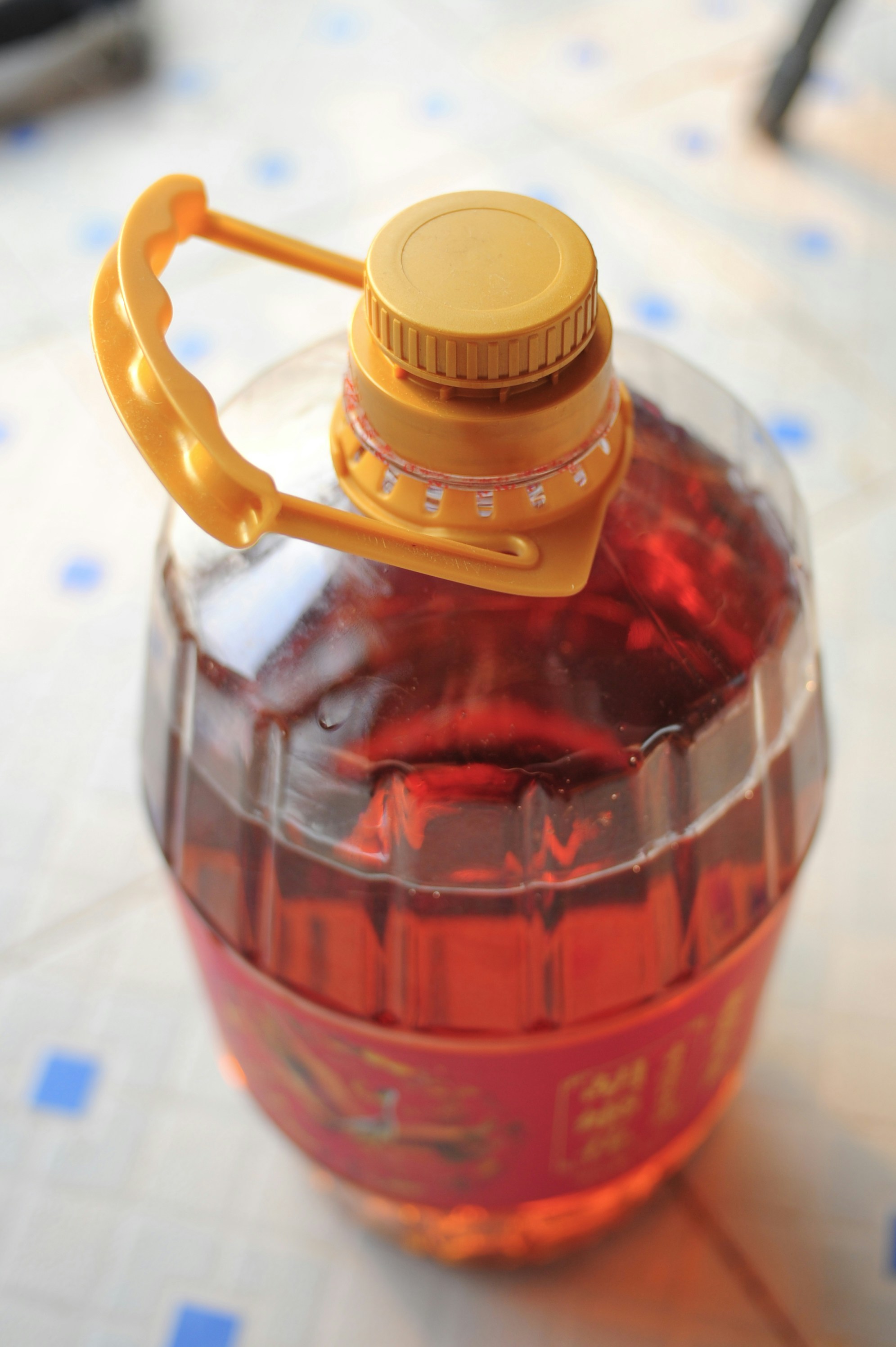 Large plastic jug of amber liquid with yellow handle.