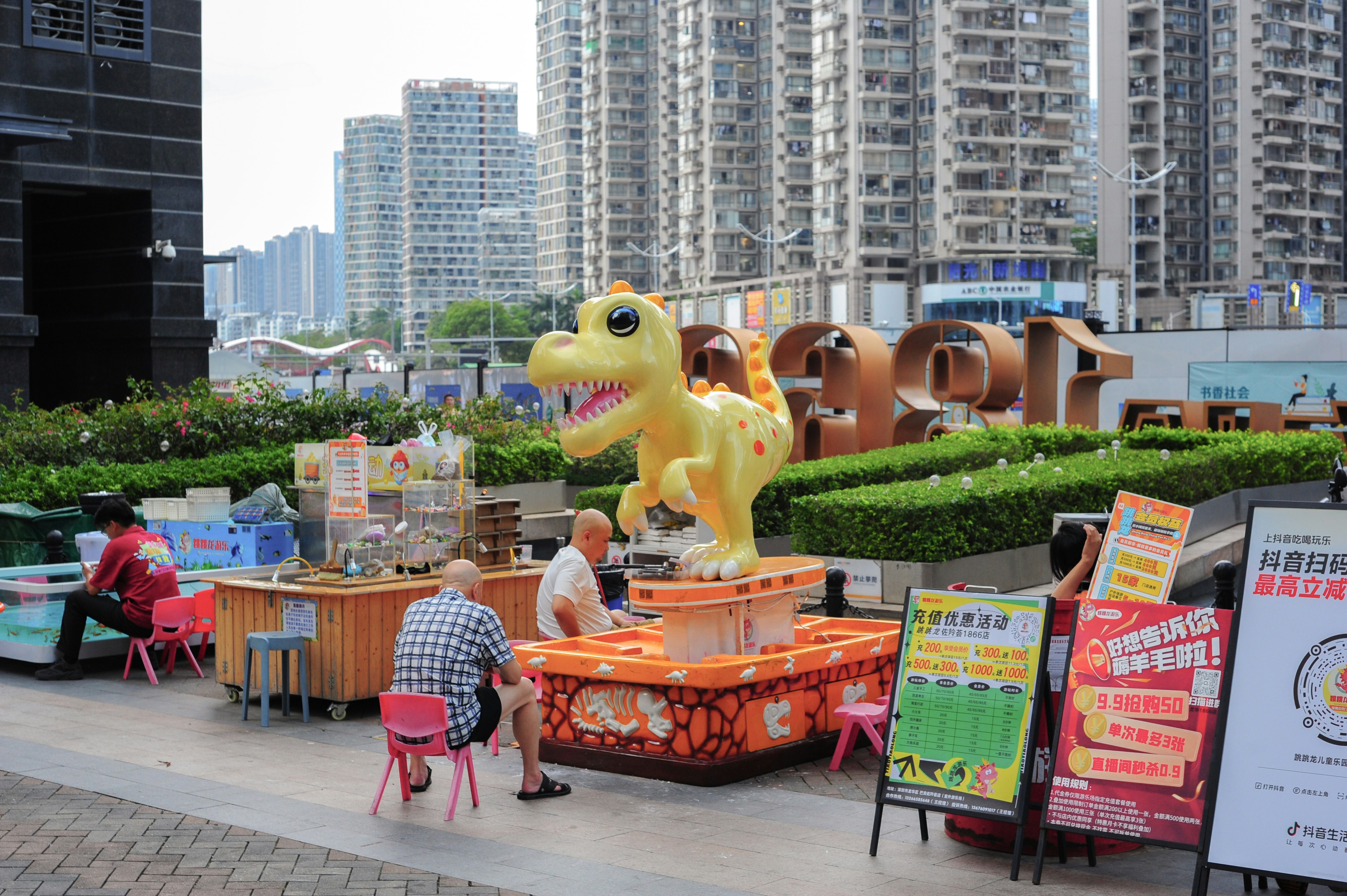 Estatua de dinosaurio amarillo en el mercado al aire libre con edificios.