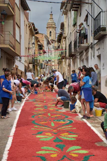 People creating a colorful carpet of petals on street.