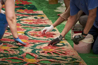 People creating a colorful carpet with sand