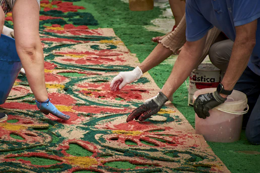 People creating a colorful carpet with sand