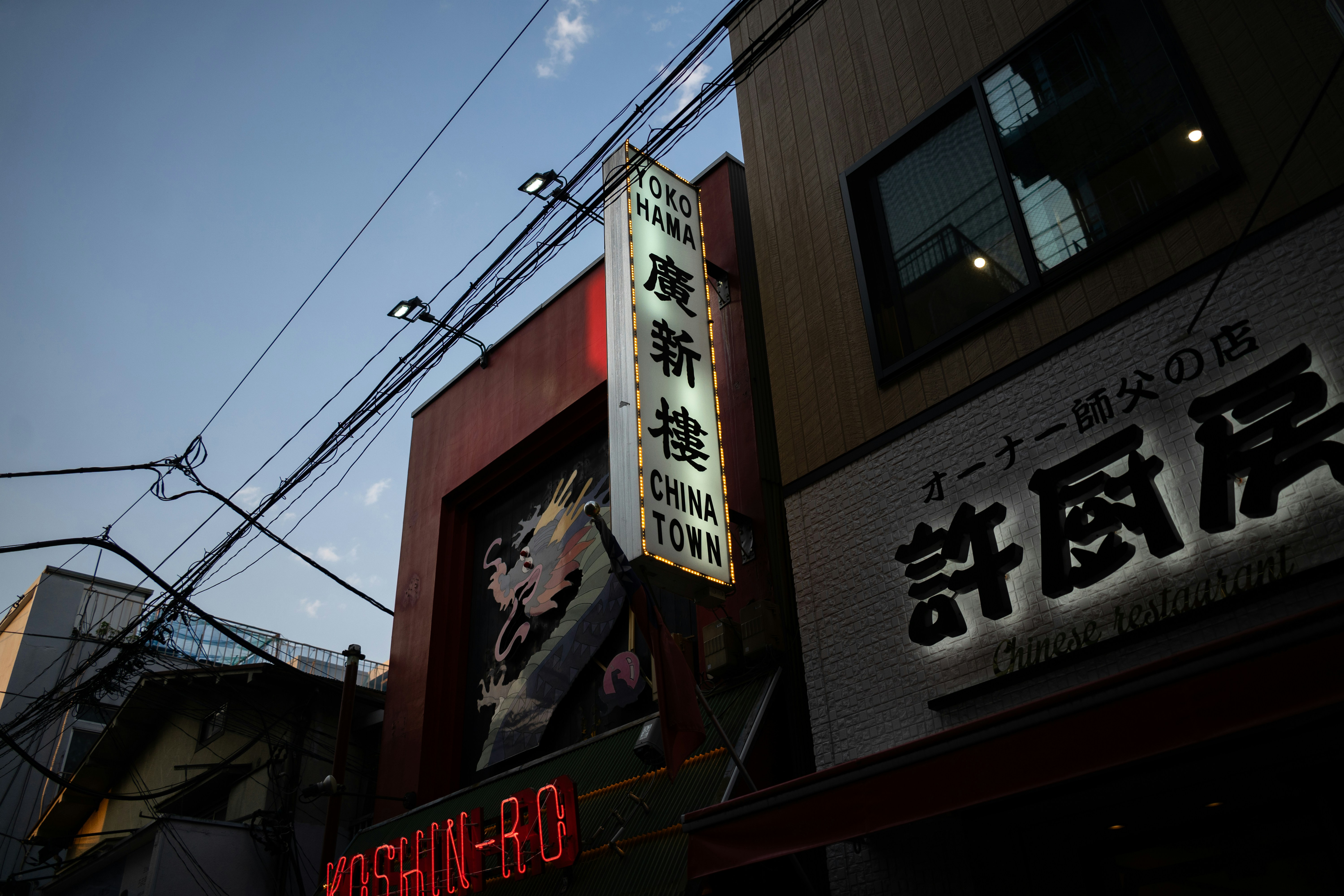 Neon signs illuminate a building at dusk.