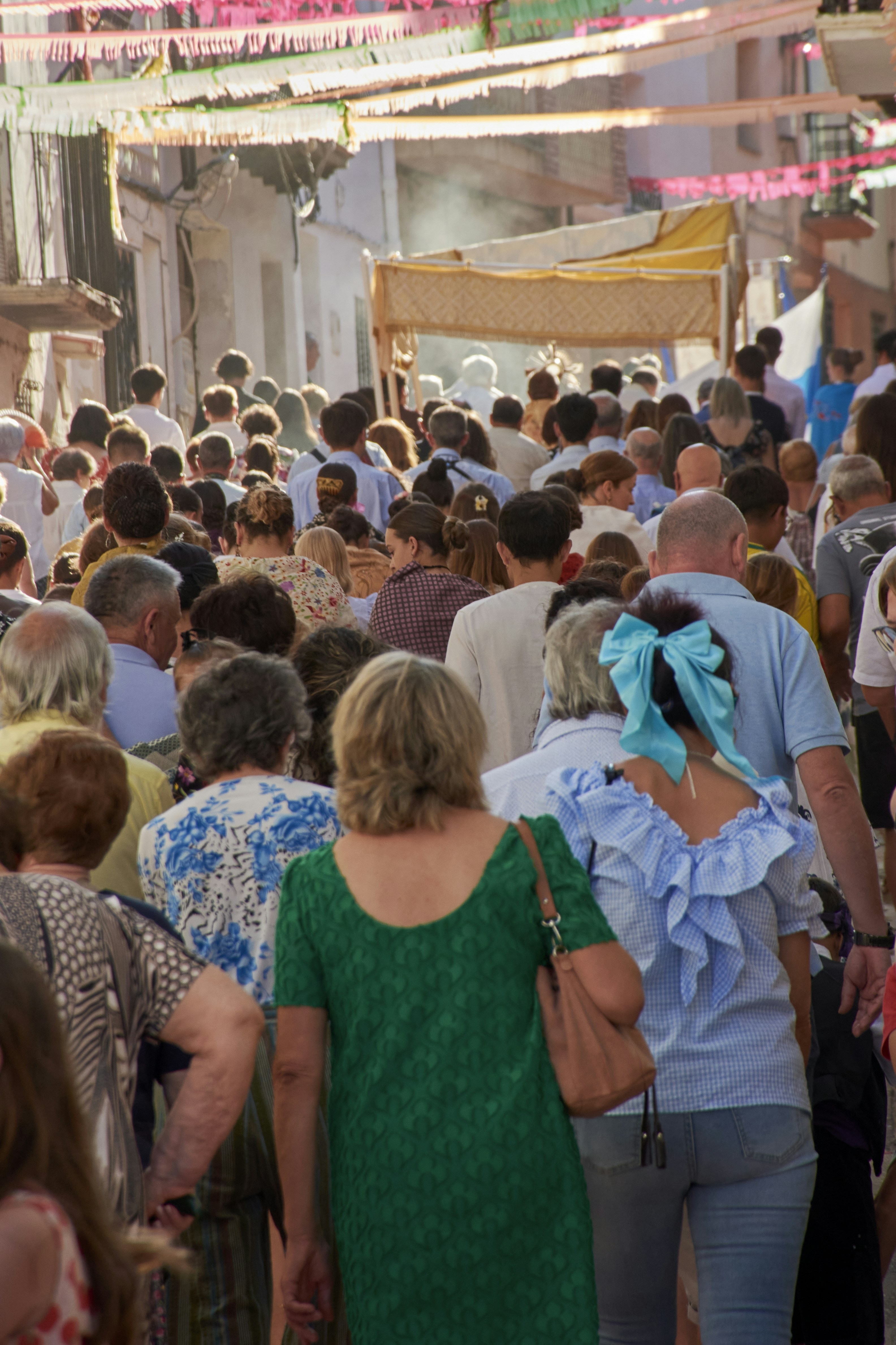 Crowd of people walking down a decorated street.