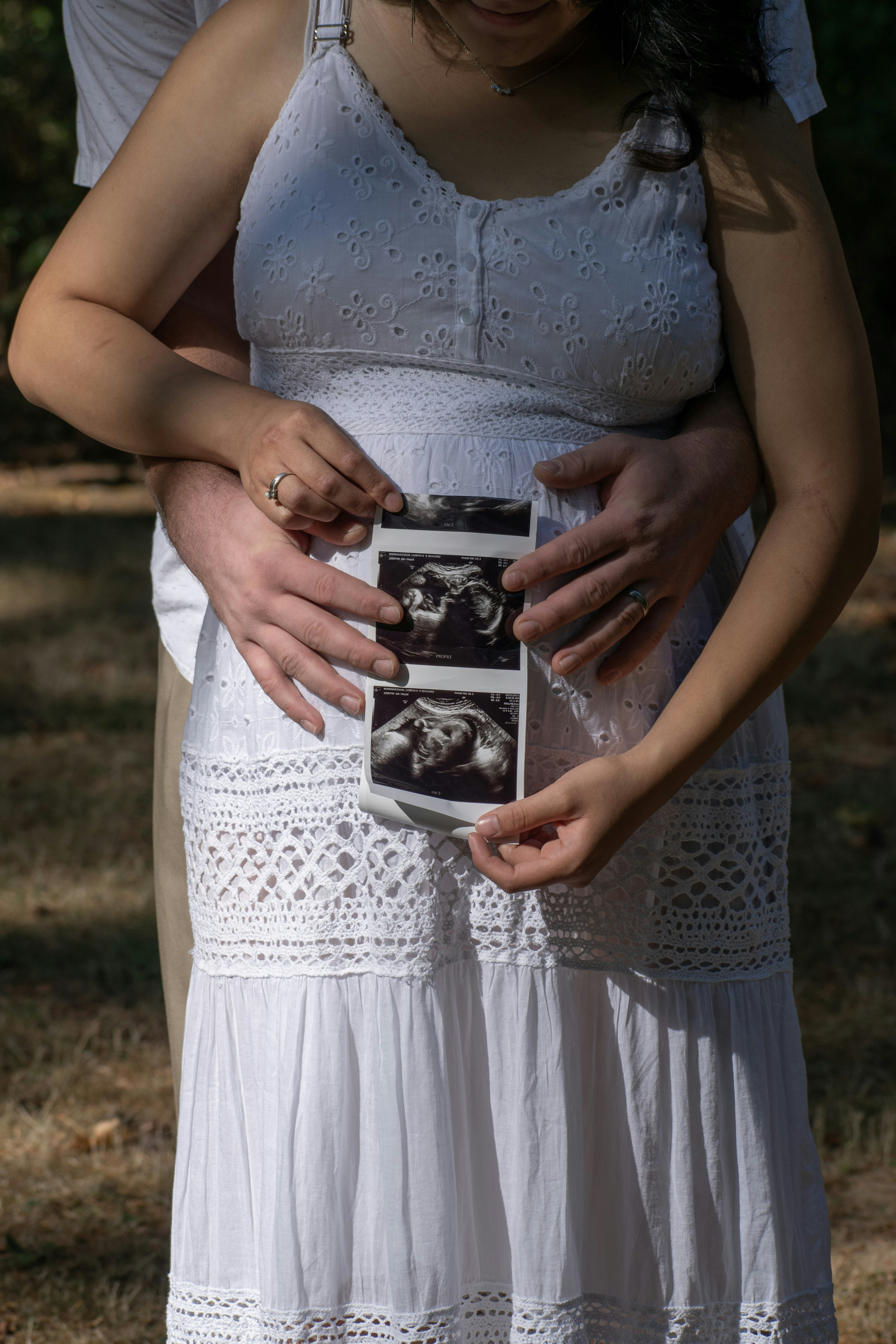 Pregnant woman holding ultrasound photos with partner