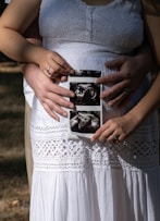 Couple holding ultrasound photos over pregnant belly.