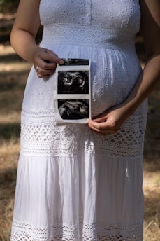 Pregnant woman holds ultrasound pictures of her baby.