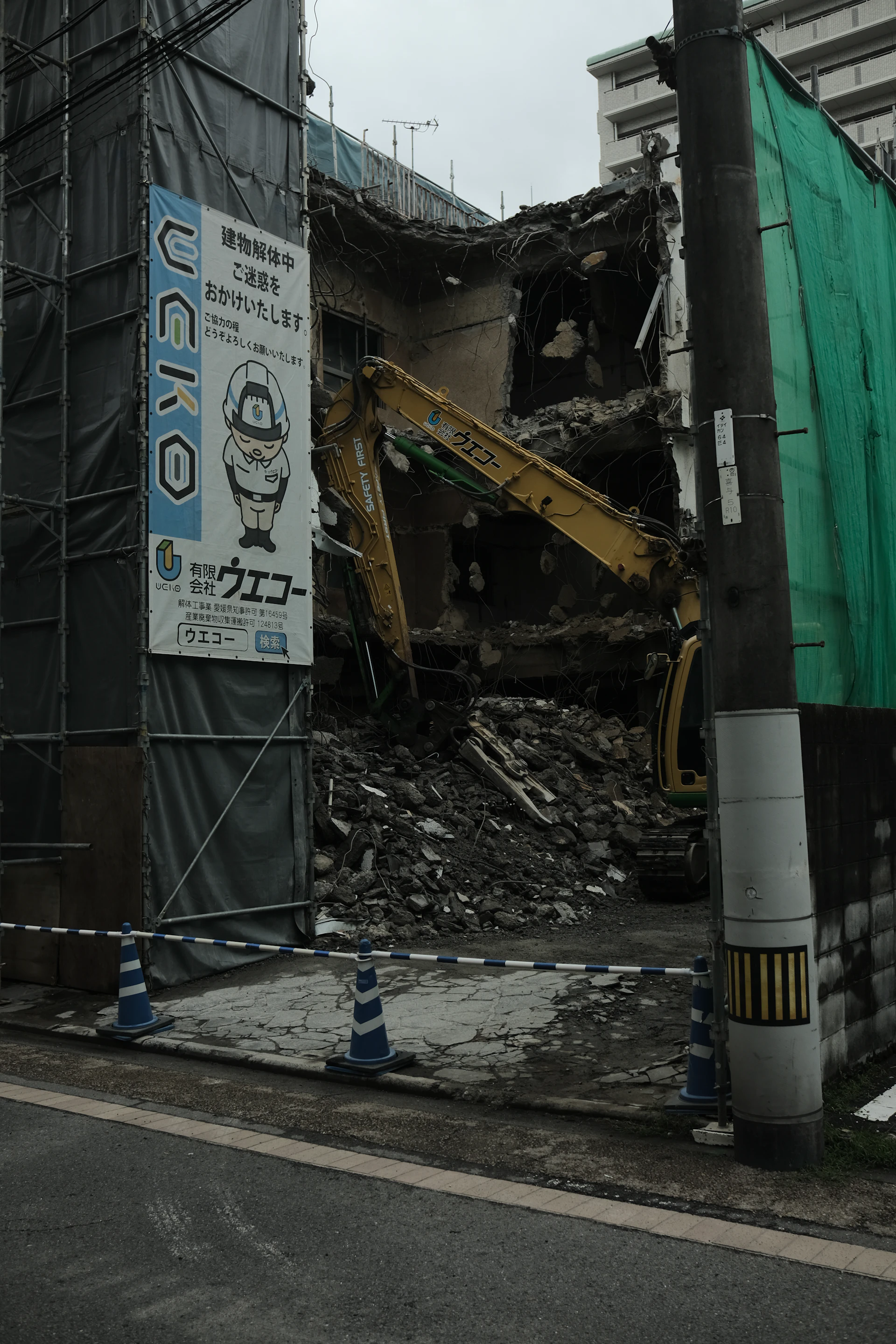 Excavator demolishing a building with a pile of debris on site