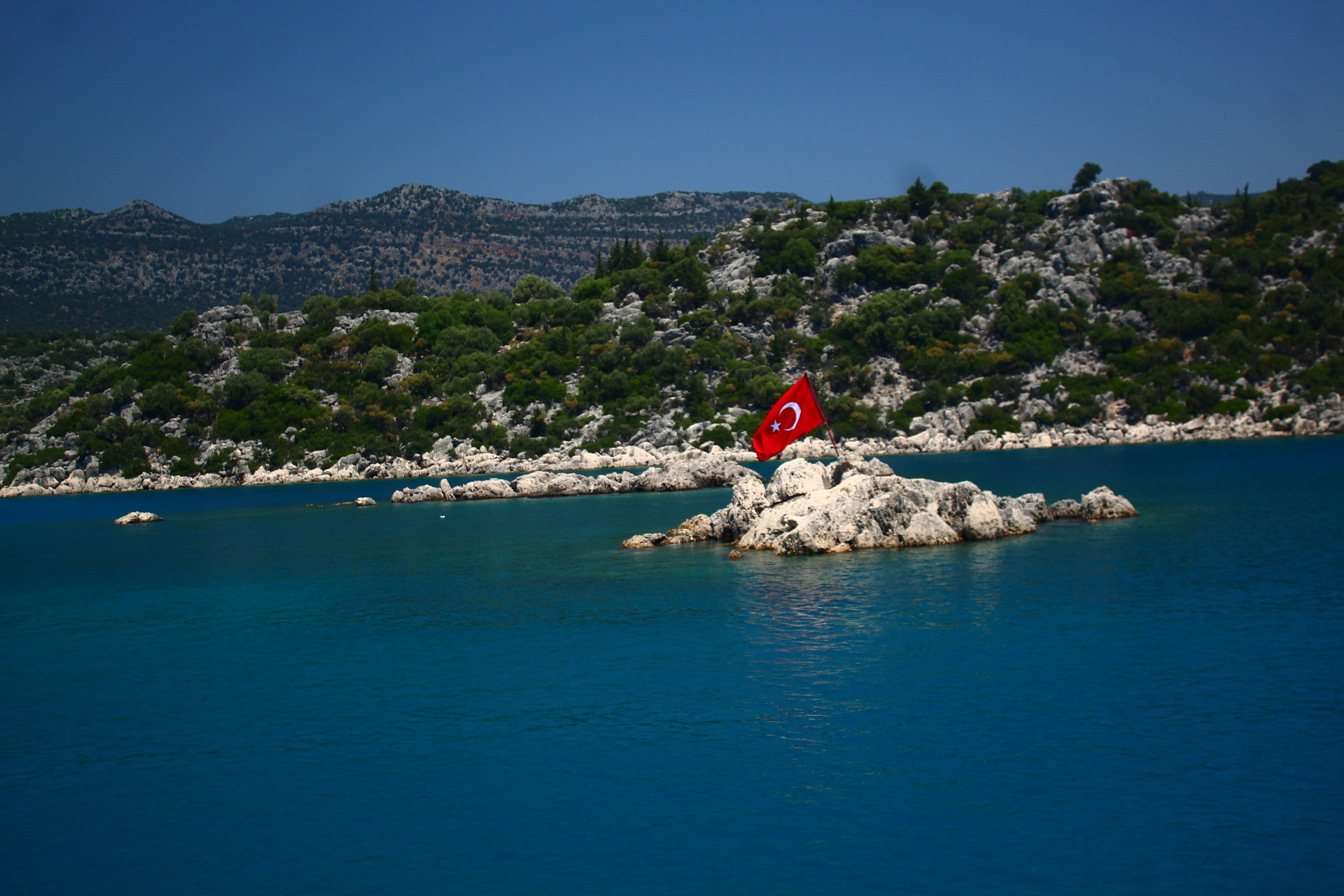 Turkish flag on rocky island in bright blue sea