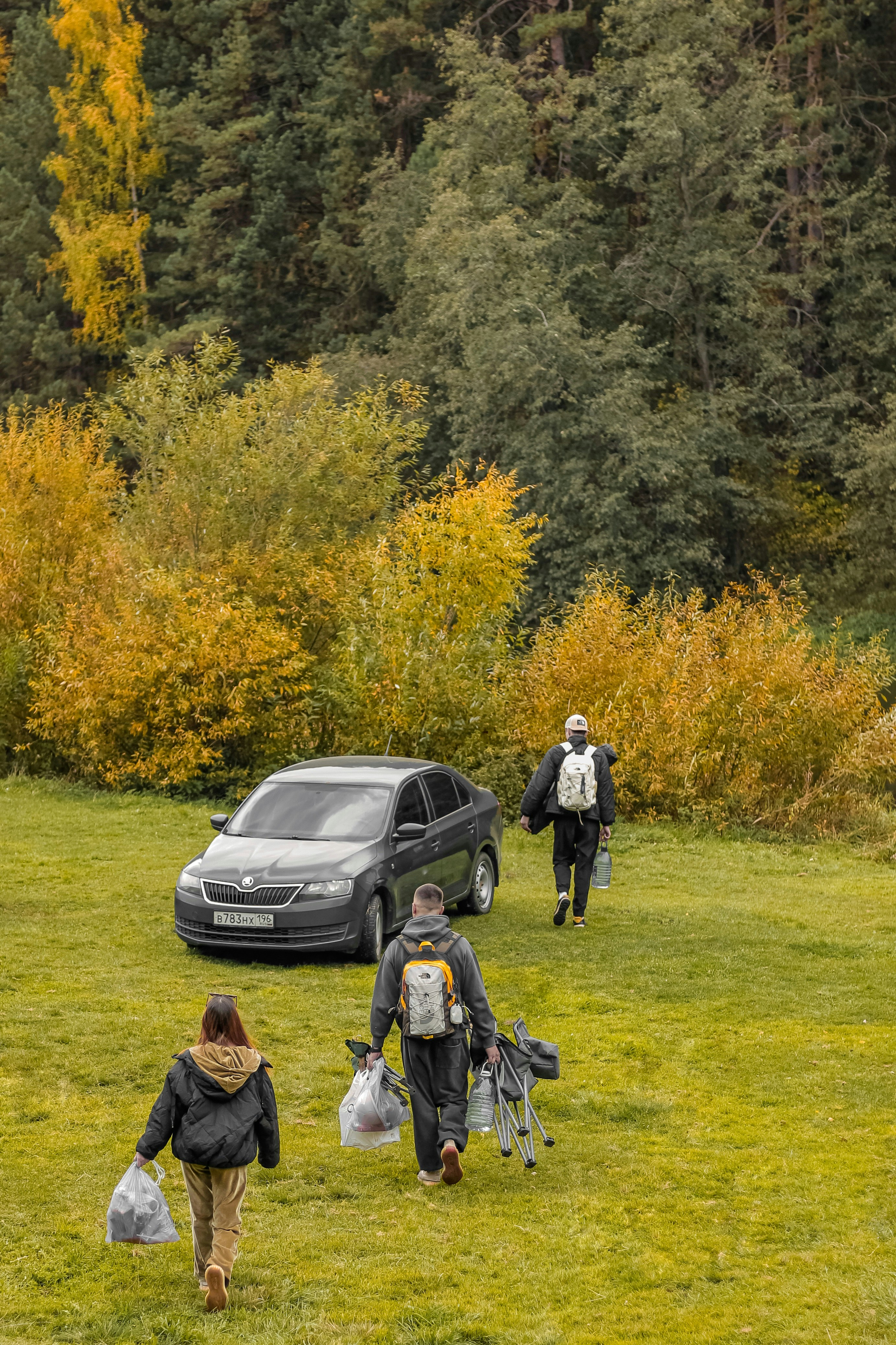 People walking towards car in autumn landscape