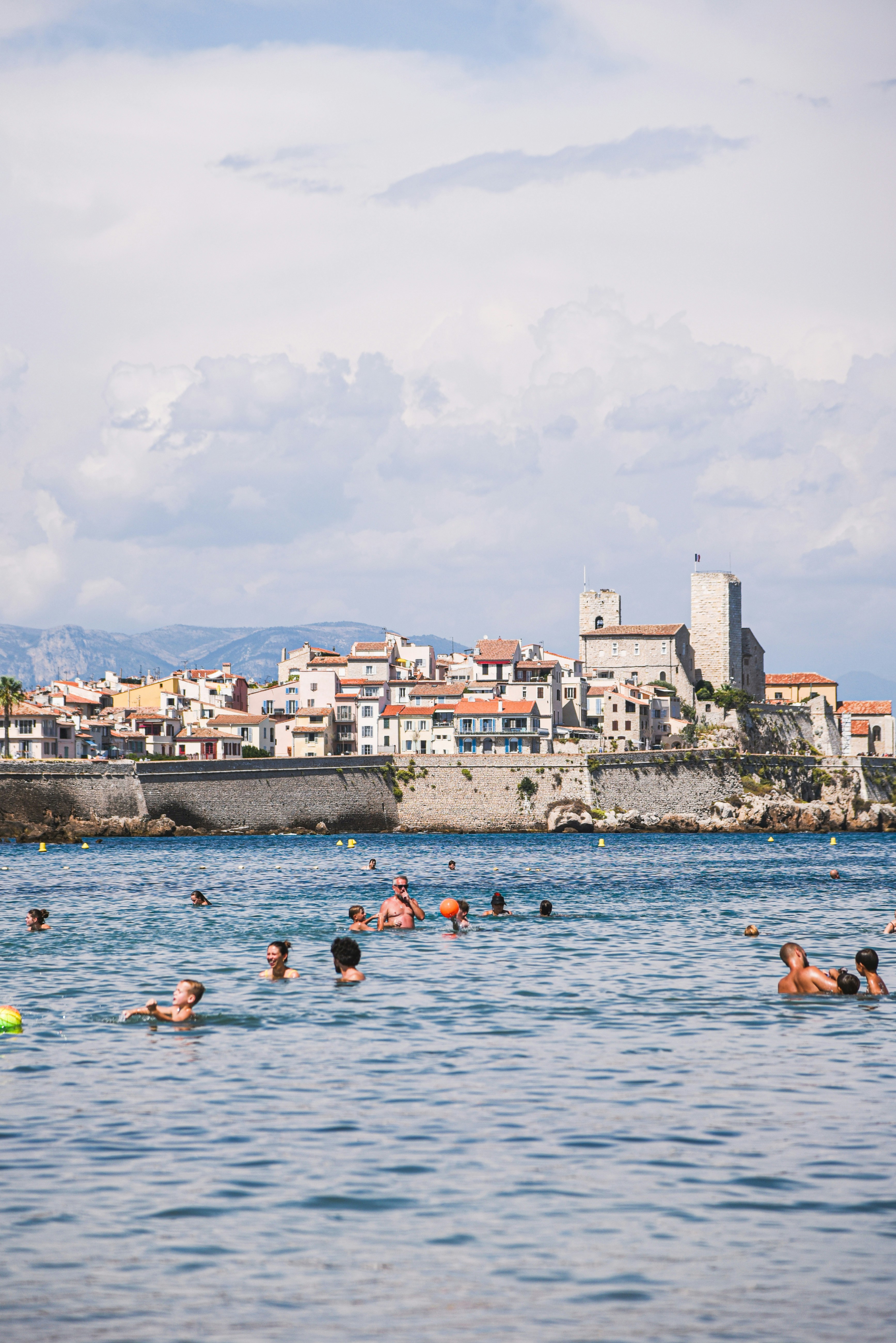 Persone che nuotano nel mare con una città costiera alle spalle.