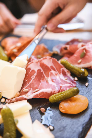 Charcuterie board with cured meats, cheese, and pickles.
