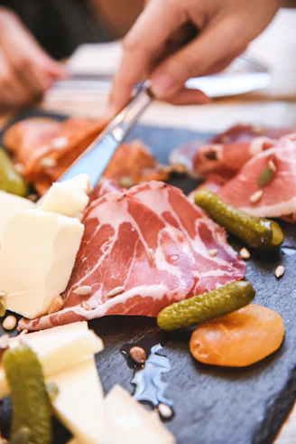 Charcuterie board with cured meats, cheese, and pickles.