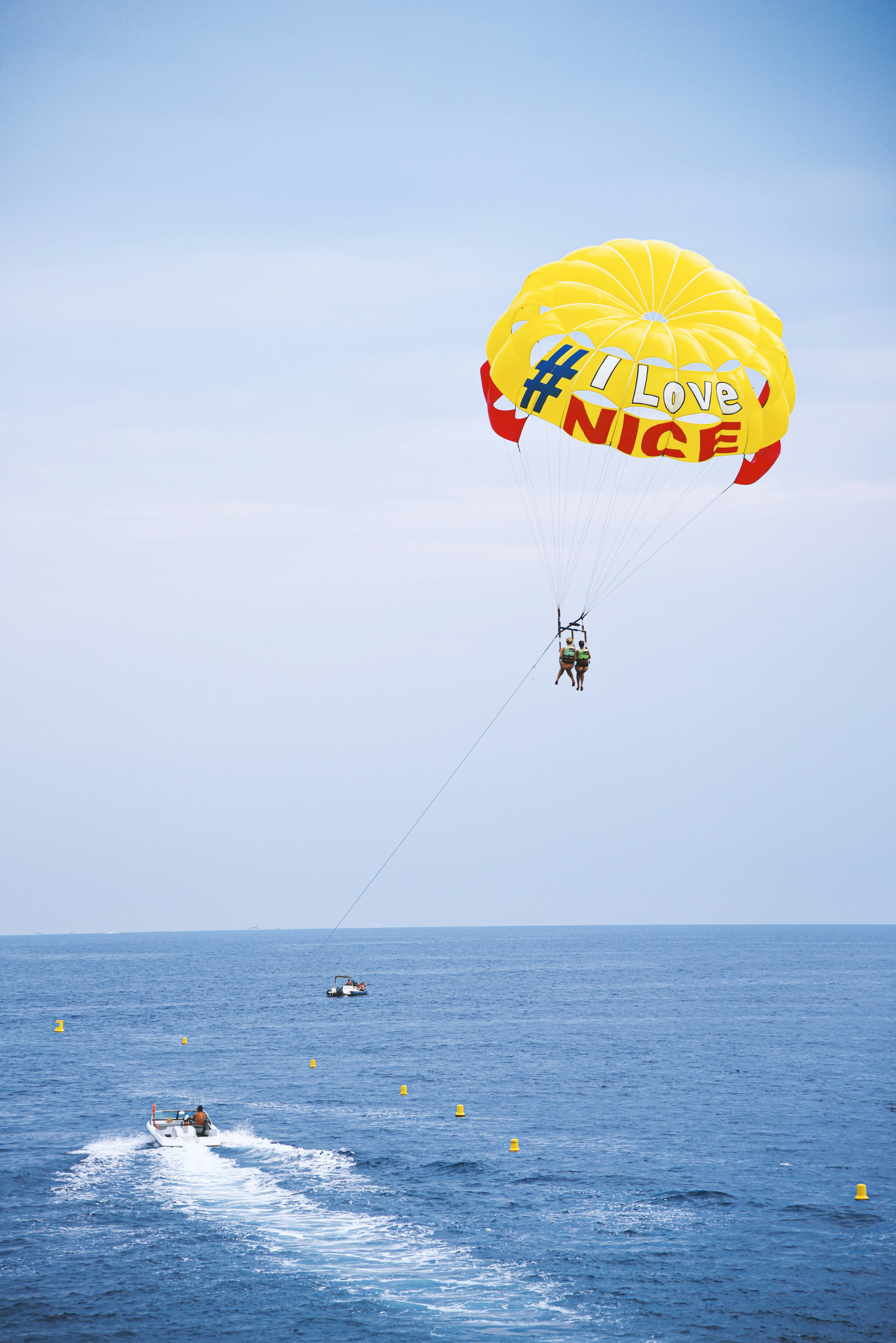 People parasailing over the ocean with a boat below.