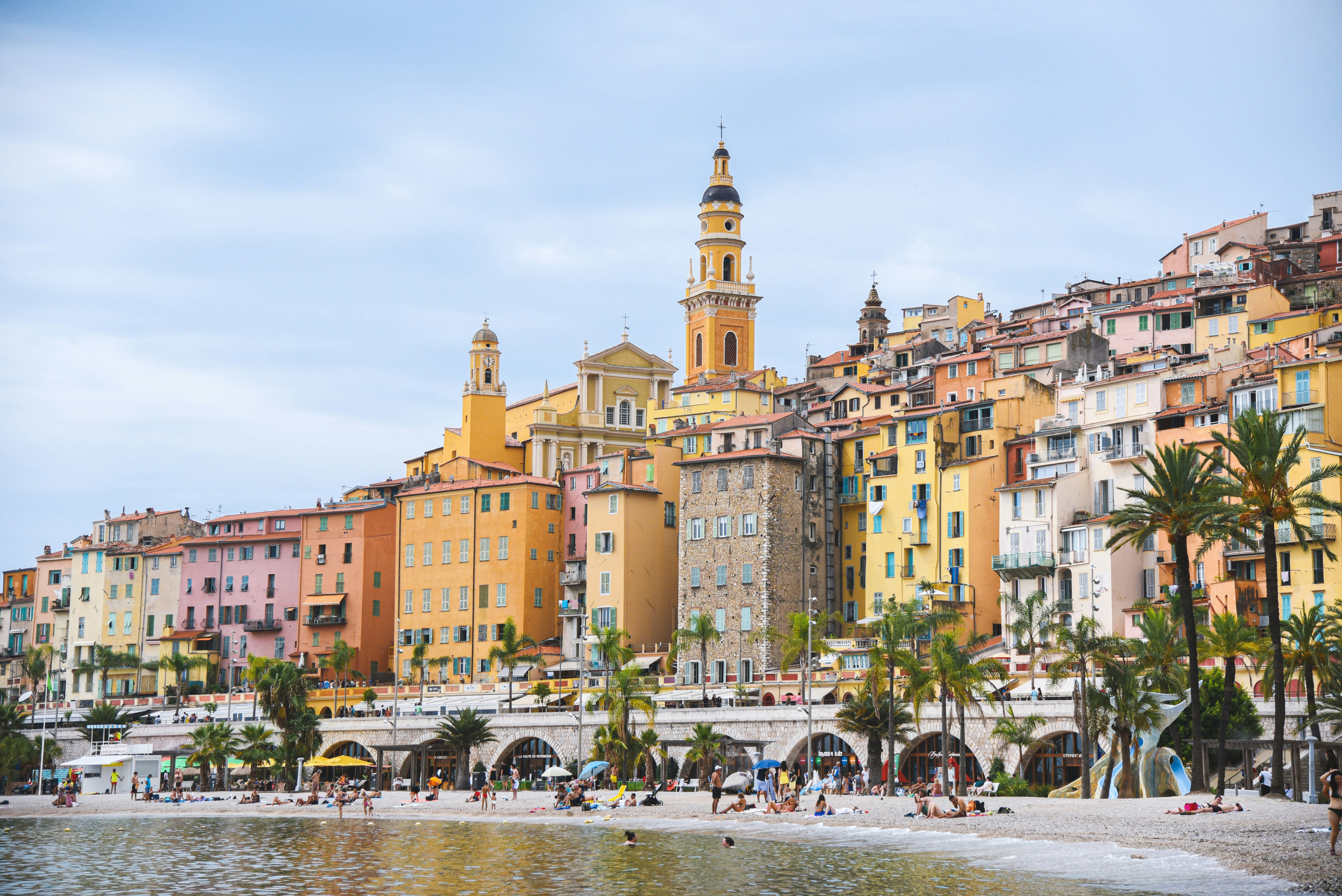 Colorful buildings line a beach with palm trees.