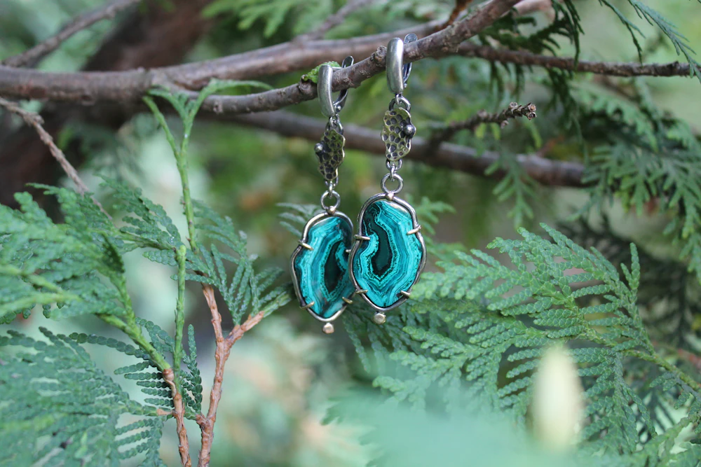 Turquoise malachite drop earrings hanging from a branch