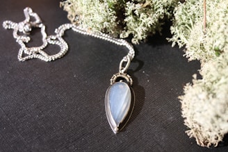 Silver necklace with a teardrop pendant on dark surface