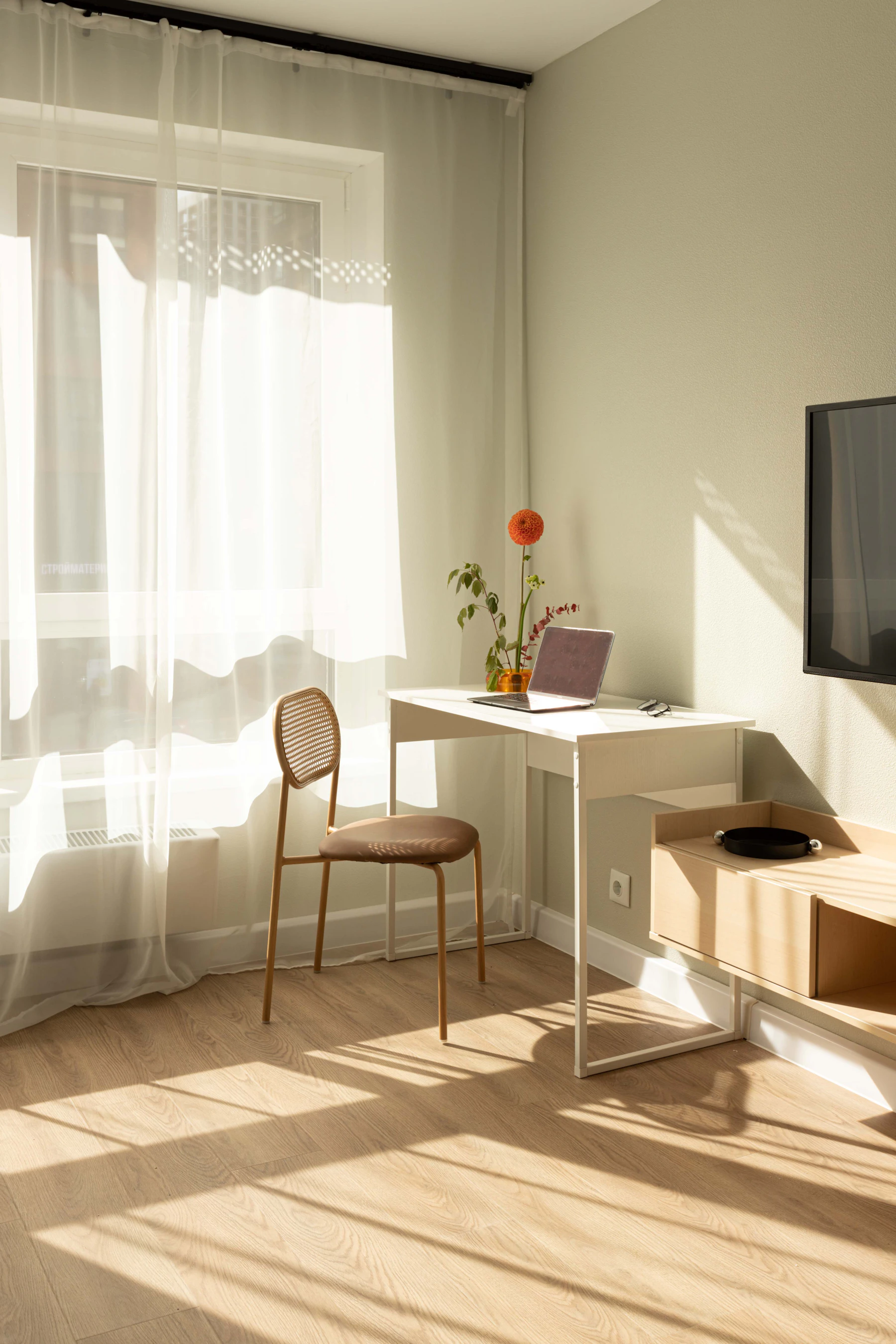 A sunlit room with a desk, a chair and an open laptop