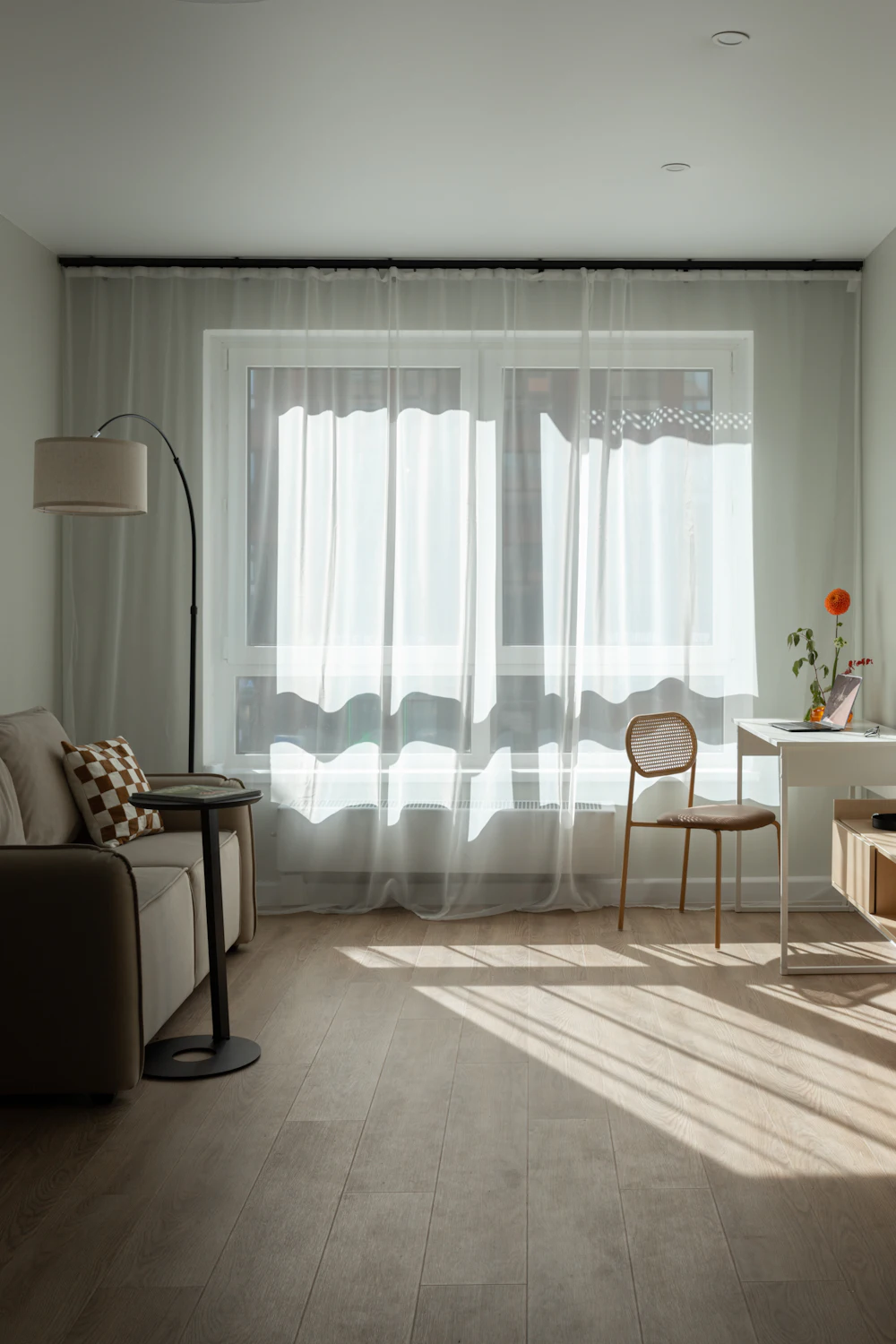 Sunlight through sheer curtains onto a living room floor