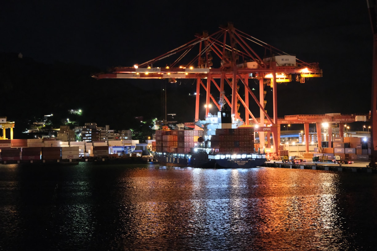 Large industrial cranes at a harbor at night.
