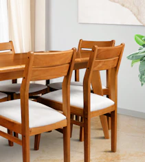 Wooden dining chairs with white cushions around table