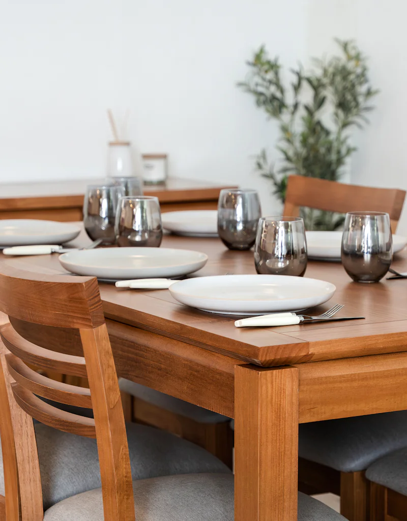 A wooden dining table set with plates and glasses