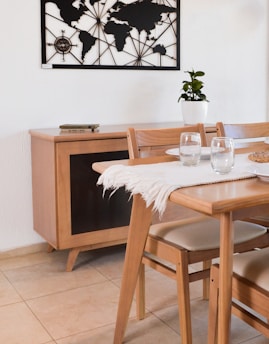 Dining table set with wooden chairs and world map decor.