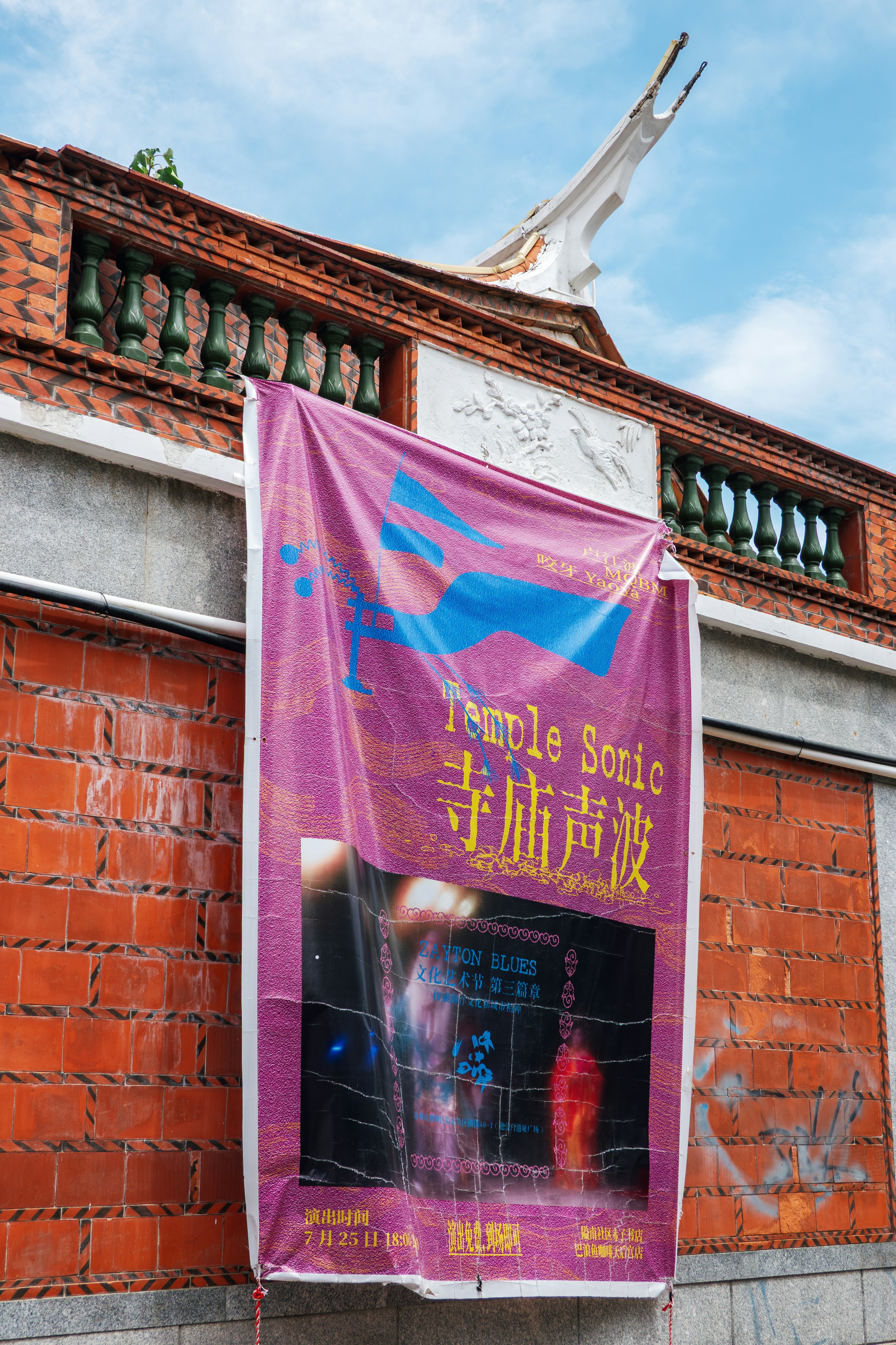 Purple banner with "temple sonic" text on brick wall.