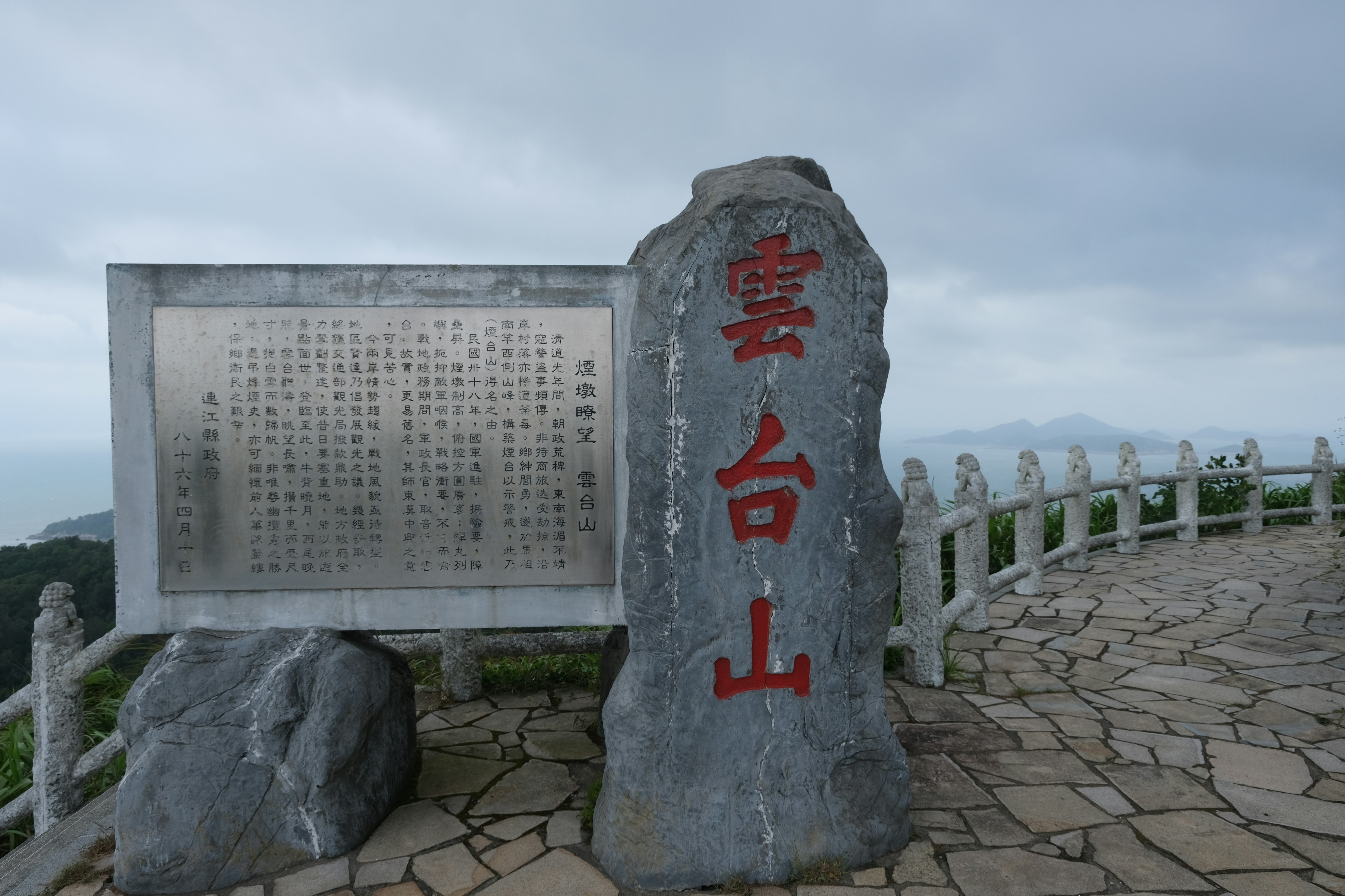 Stone monument with chinese characters on a mountain path.