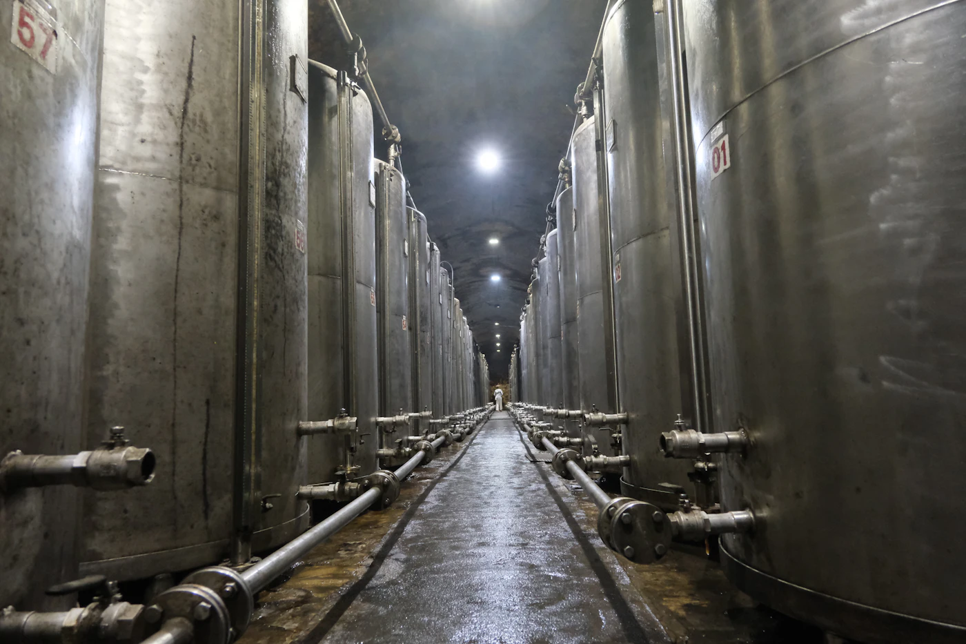 Stainless steel tanks and pipework along an industrial hallway