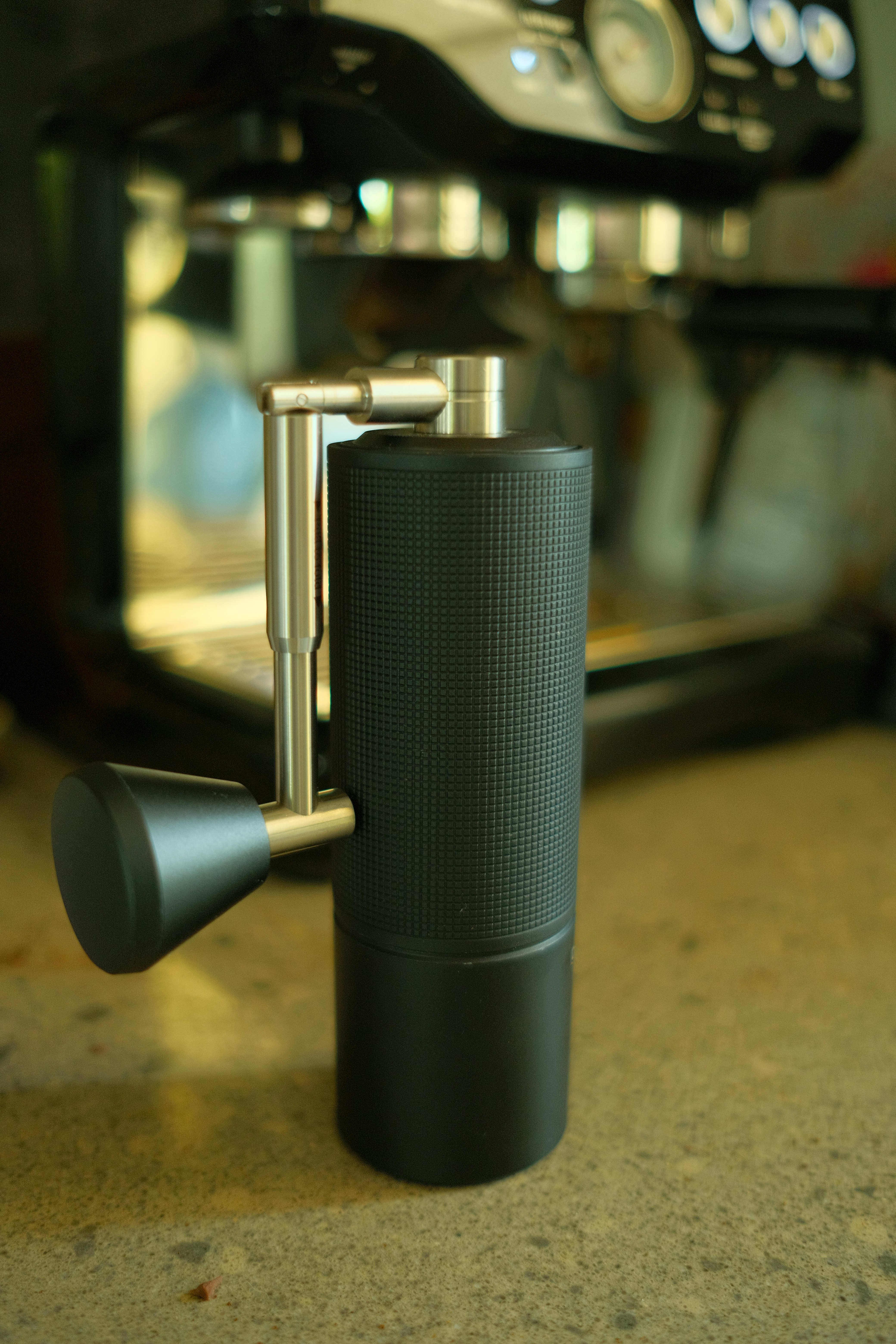 Manual coffee grinder in front of espresso machine