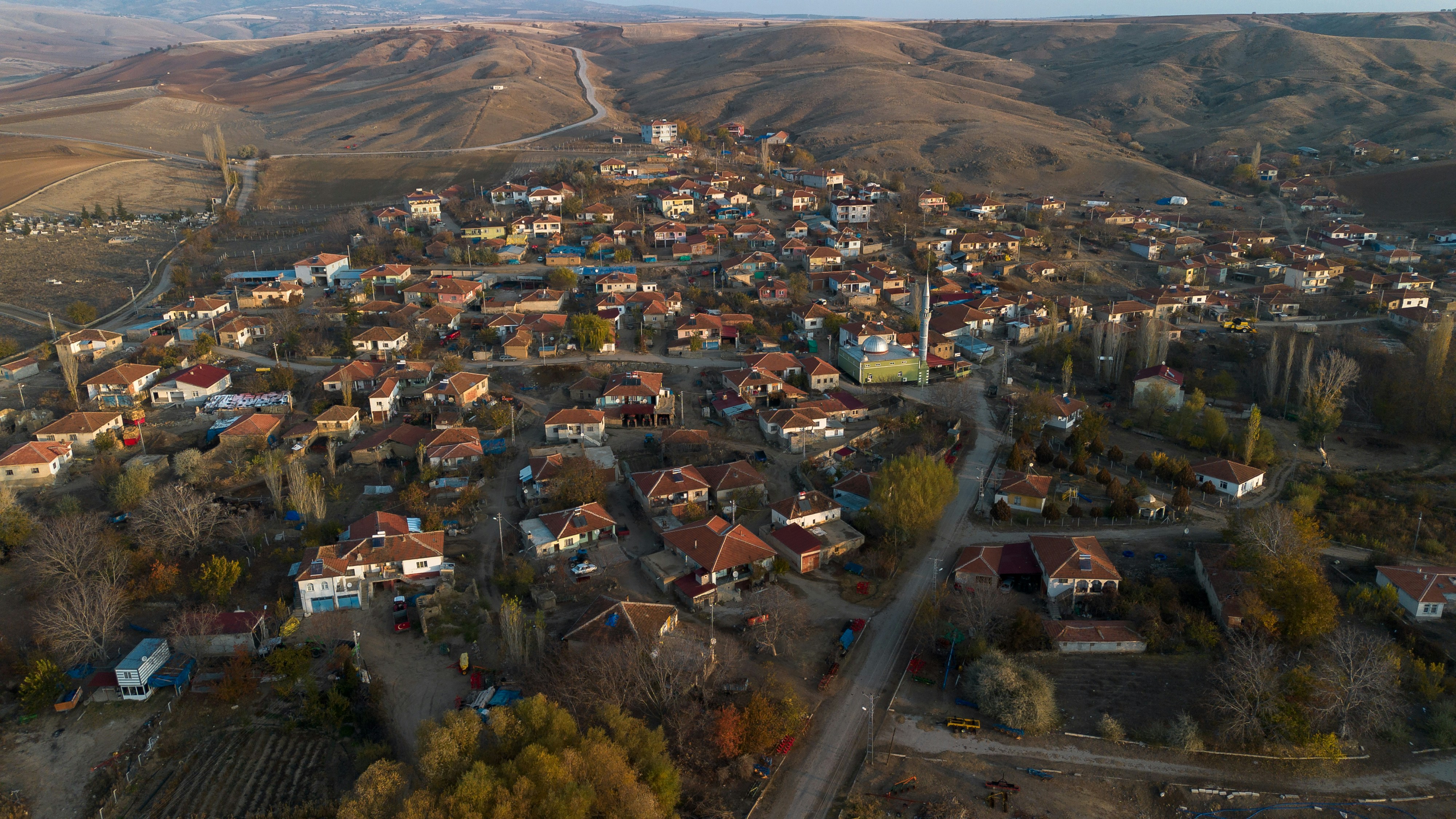 Aerial view of a small village nestled in rolling hills.