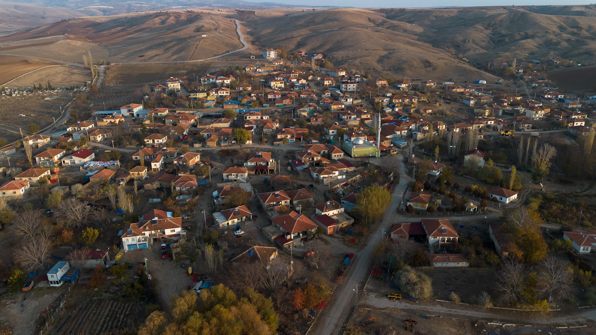 Aerial view of a small village nestled in rolling hills.