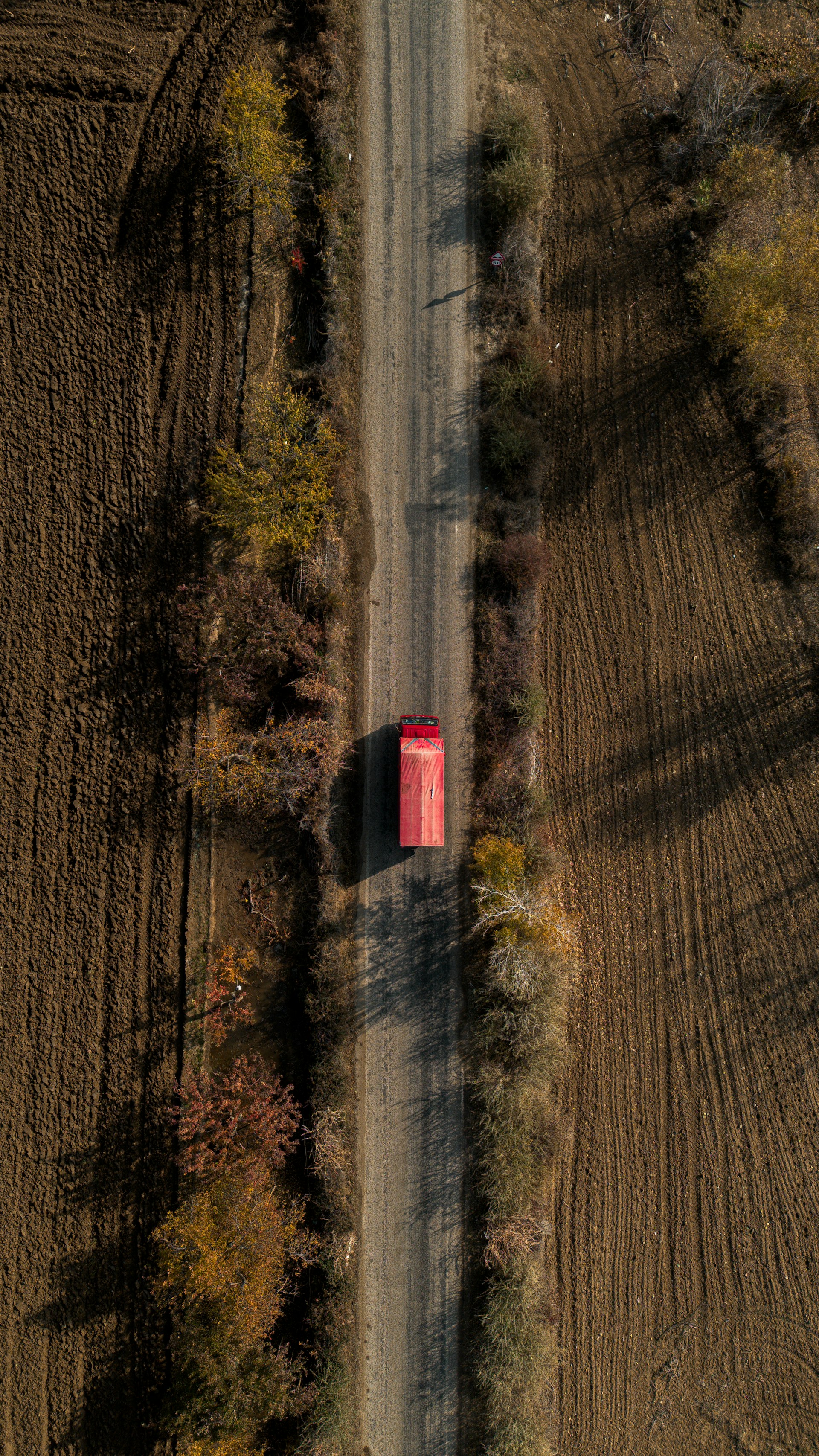 A red truck drives down a rural road.